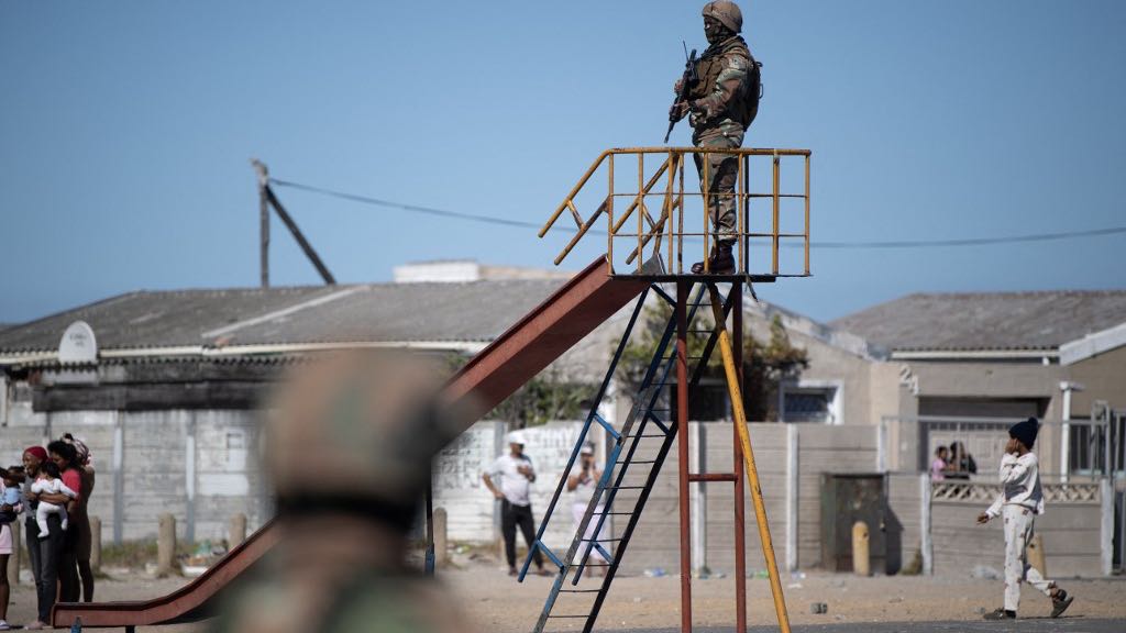 A soldier of the South African National Defence Force (SANDF) stands on a slide in a playground during a patrol as part of Operation Prosper in Mitchells Plain, near Cape Town, on April 1, 2026. Operation Prosper sees the SANDF play a supporting role to the South African Police Service (SAPS) in crime prevention operations. RODGER BOSCH / AFP