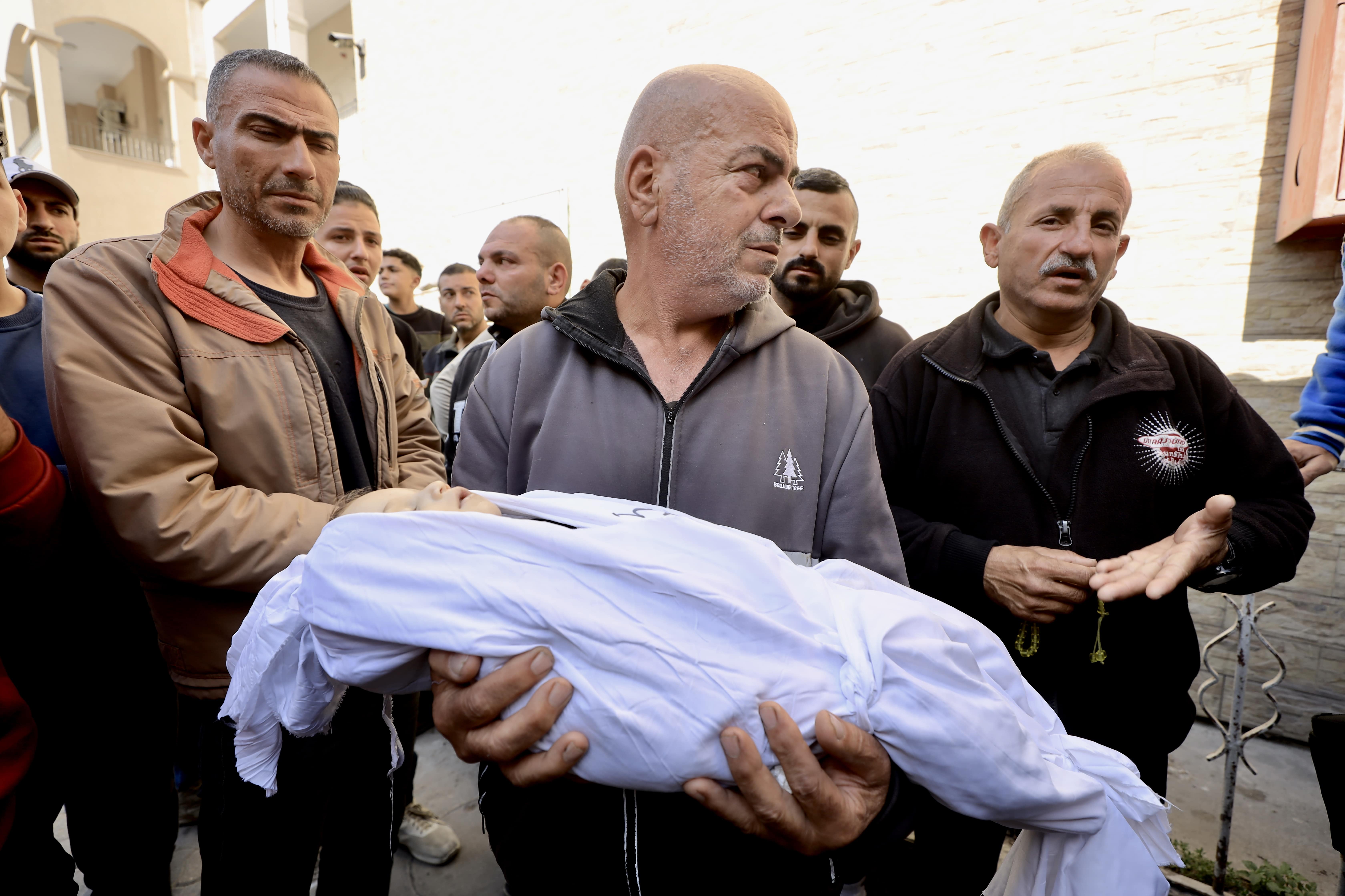 A Palestinian man carries a child killed during Israeli strikes on Gaza on 18 March, 2025 (MEE/Mohammed al-Hajjar)