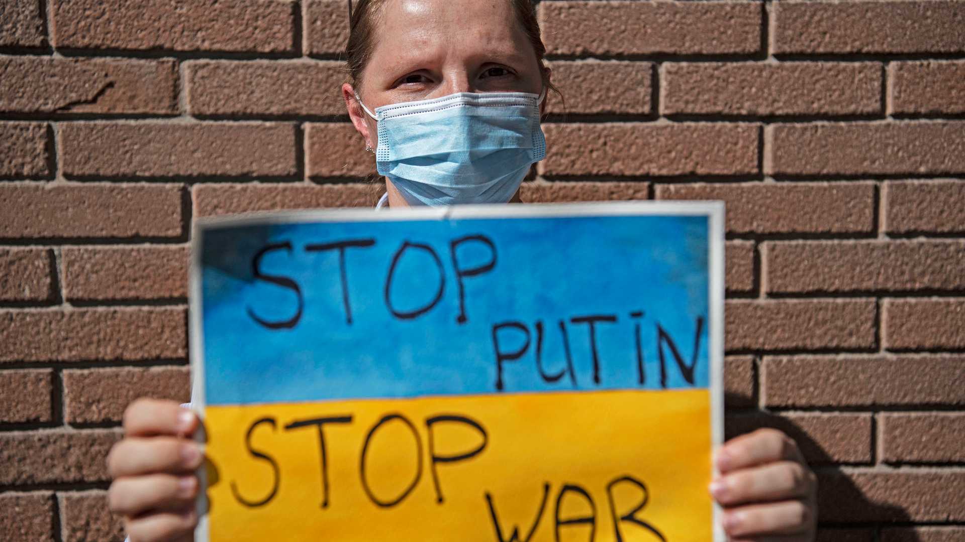 An Ukrainian woman holds a poster during a protest in support of Ukraine in front of the Russian Embassy in Santiago, on February 24, 2022.
