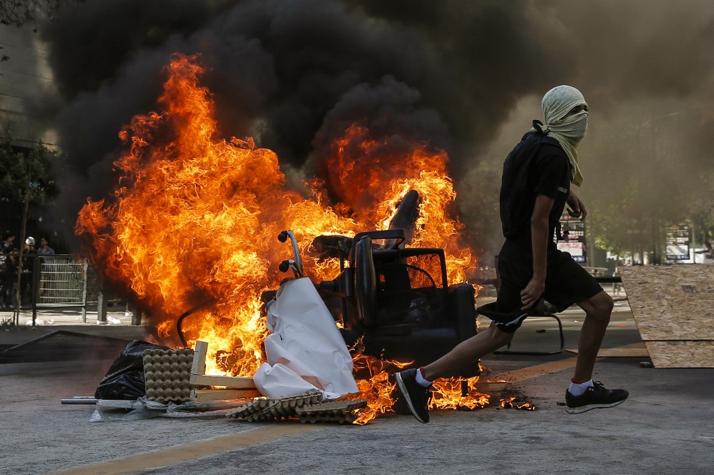 A Chilean demonstrator runs during a protest in Santiago on 6 November (AFP)