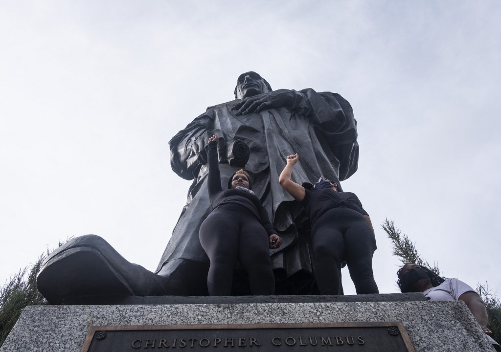 People protest at the base of a Christopher Columbus statue in Ohio in June 2020 (AFP)