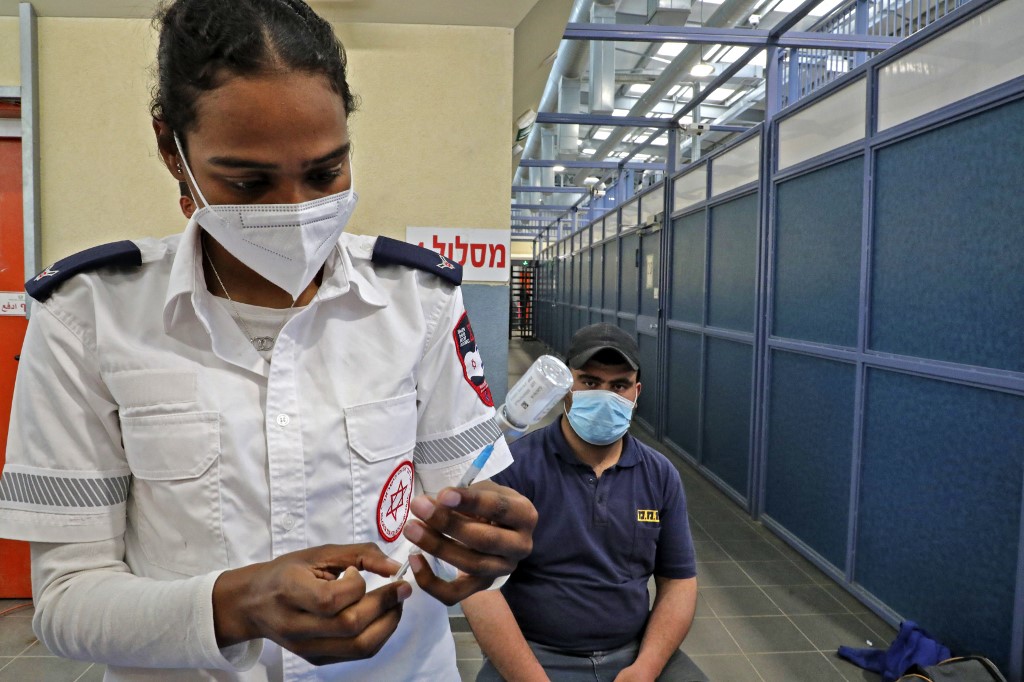 A Palestinian man working in Israel receives a Covid-19 vaccine at the Mitar checkpoint south of Hebron in the occupied West Bank on 8 March 2021 (AFP)
