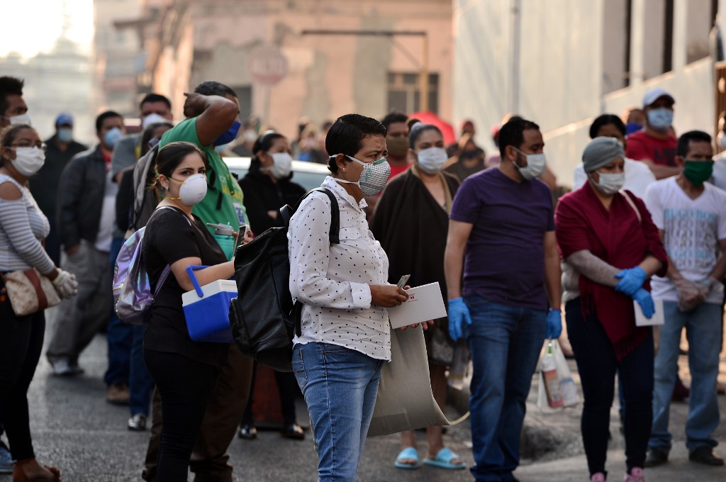 People queue in a street of Tegucigalpa on 6 April (AFP)