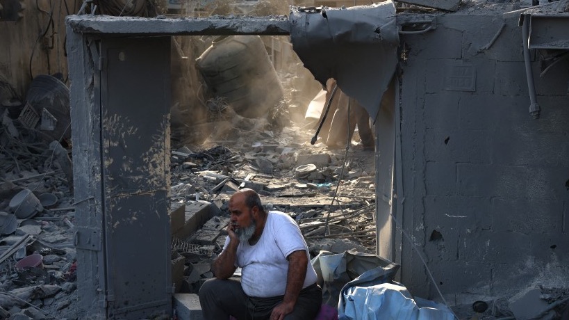 A Palestinian man sits on the debris of a house after overnight Israeli strikes on Rafah in the southern Gaza Strip on October 22, 2023 (AFP)