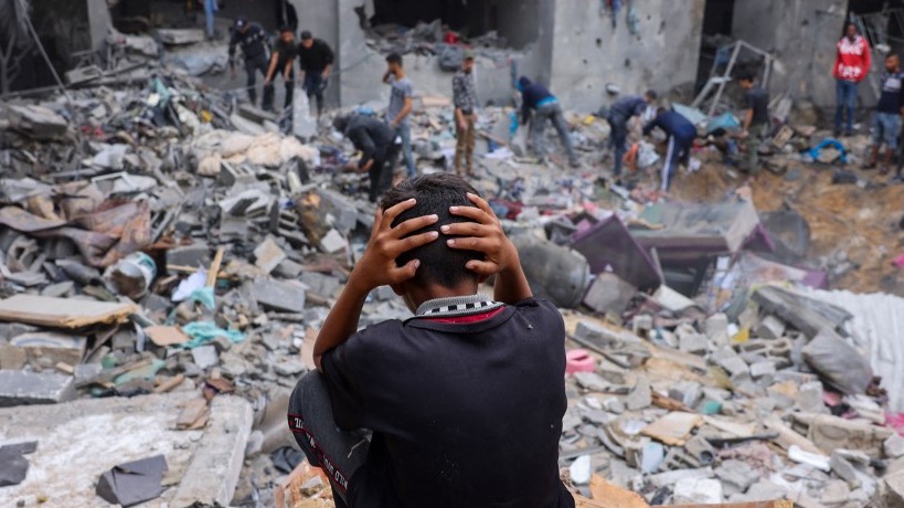 A young boy looks on in horror after Israel destroyed his family home in Rafah (Reuters)