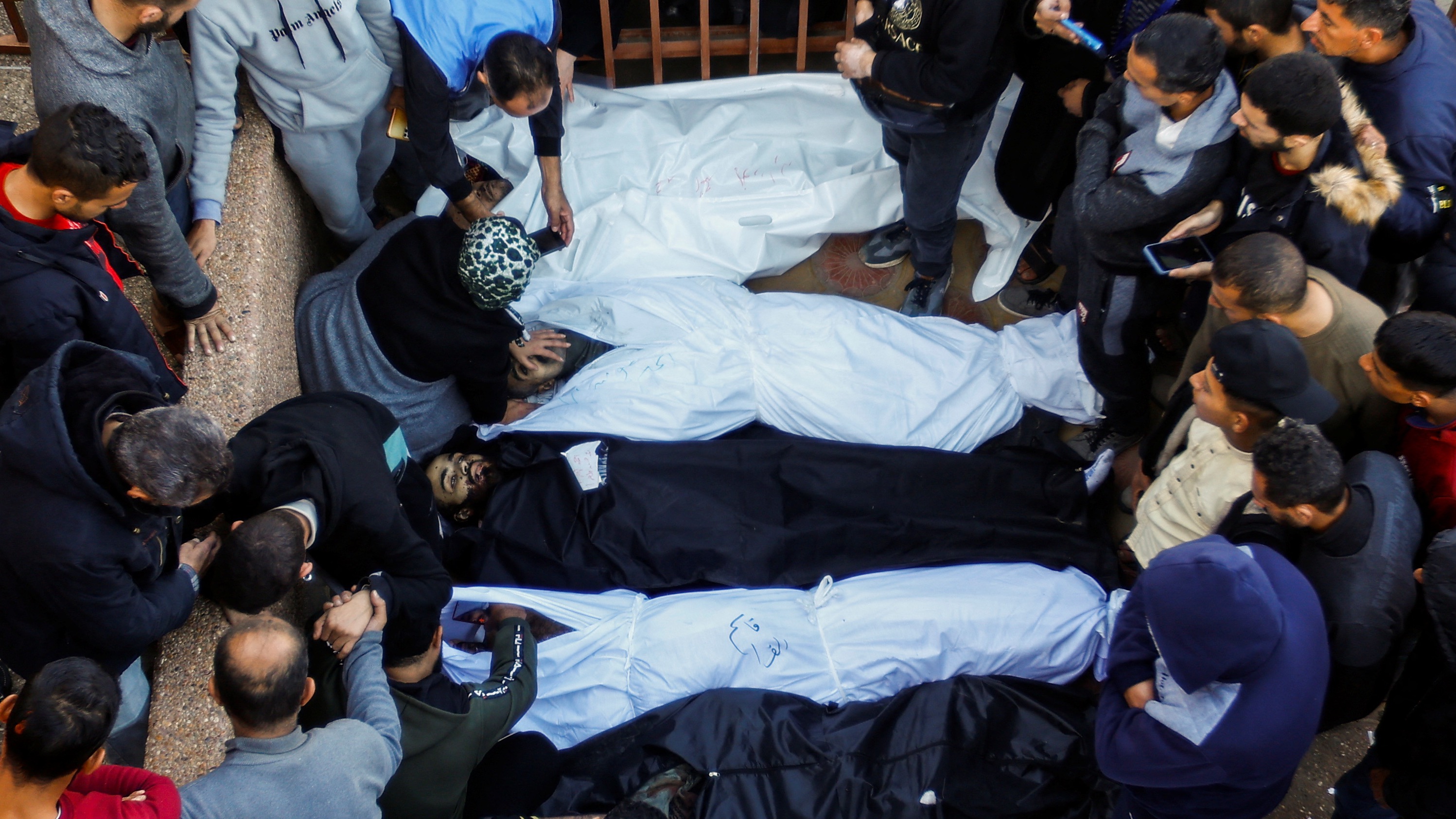 People mourn next to the bodies of Palestinians killed in Israeli strikes, during a funeral at Nasser hospital in Khan Younis