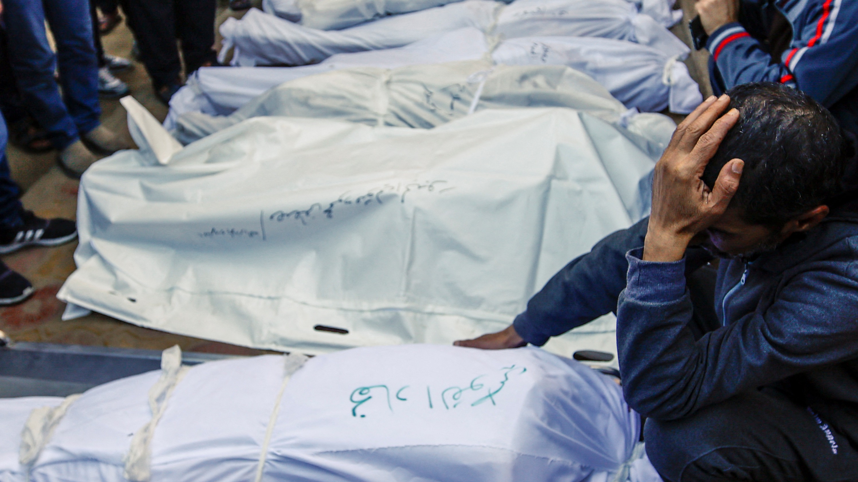 People mourn next to the bodies of Palestinians killed in Israeli strikes, during a funeral at Nasser hospital in Khan Younis
