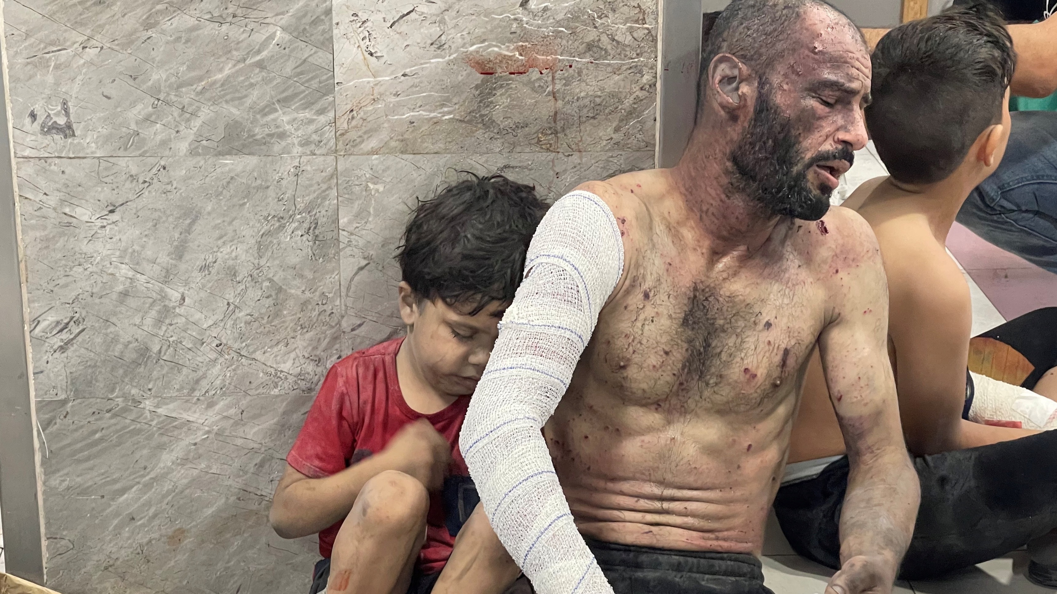 A Palestinian man and his son, who were wounded in an Israeli strike, sit on the floor at Shifa hospital in Gaza City, October 23, 2023. REUTERS/Mohammed Al-Masri