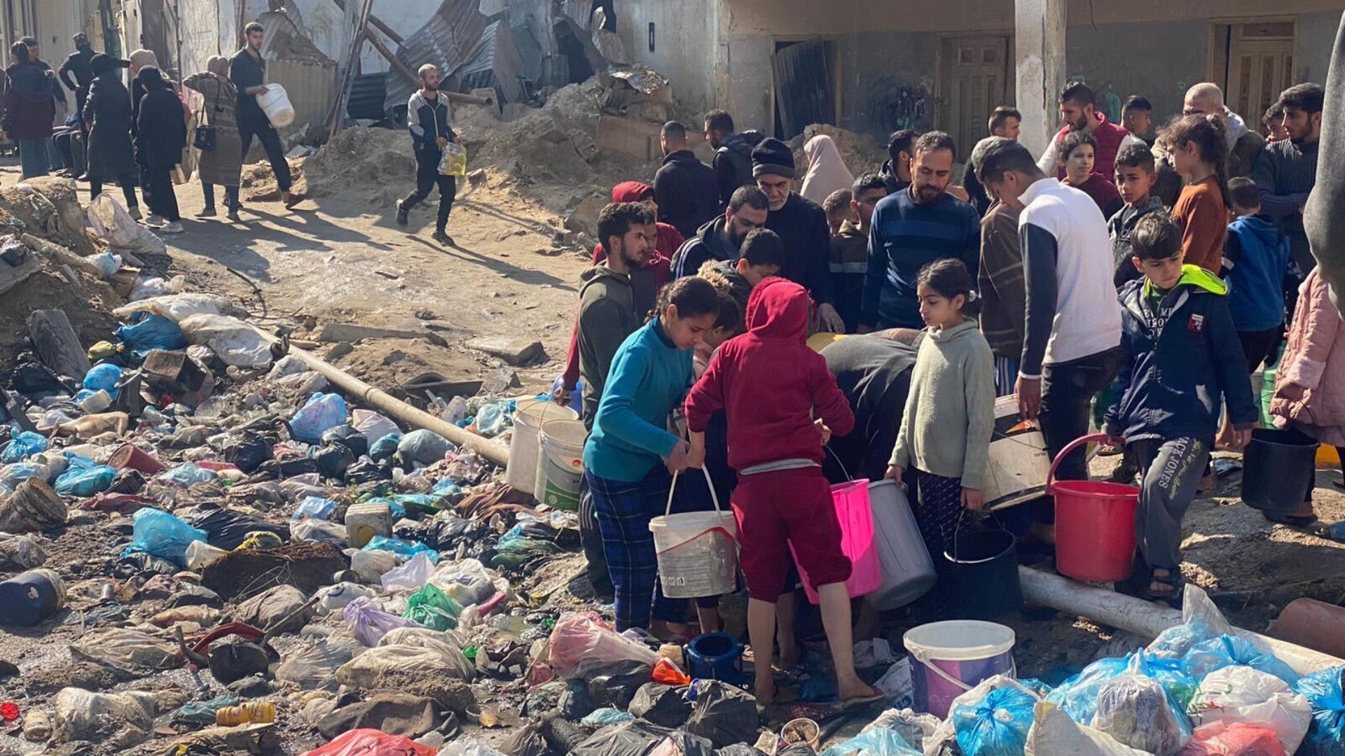 People attempt to get water a pipe damaged by Israeli air strikes in Gaza City on 10 February 2024 (MEE)