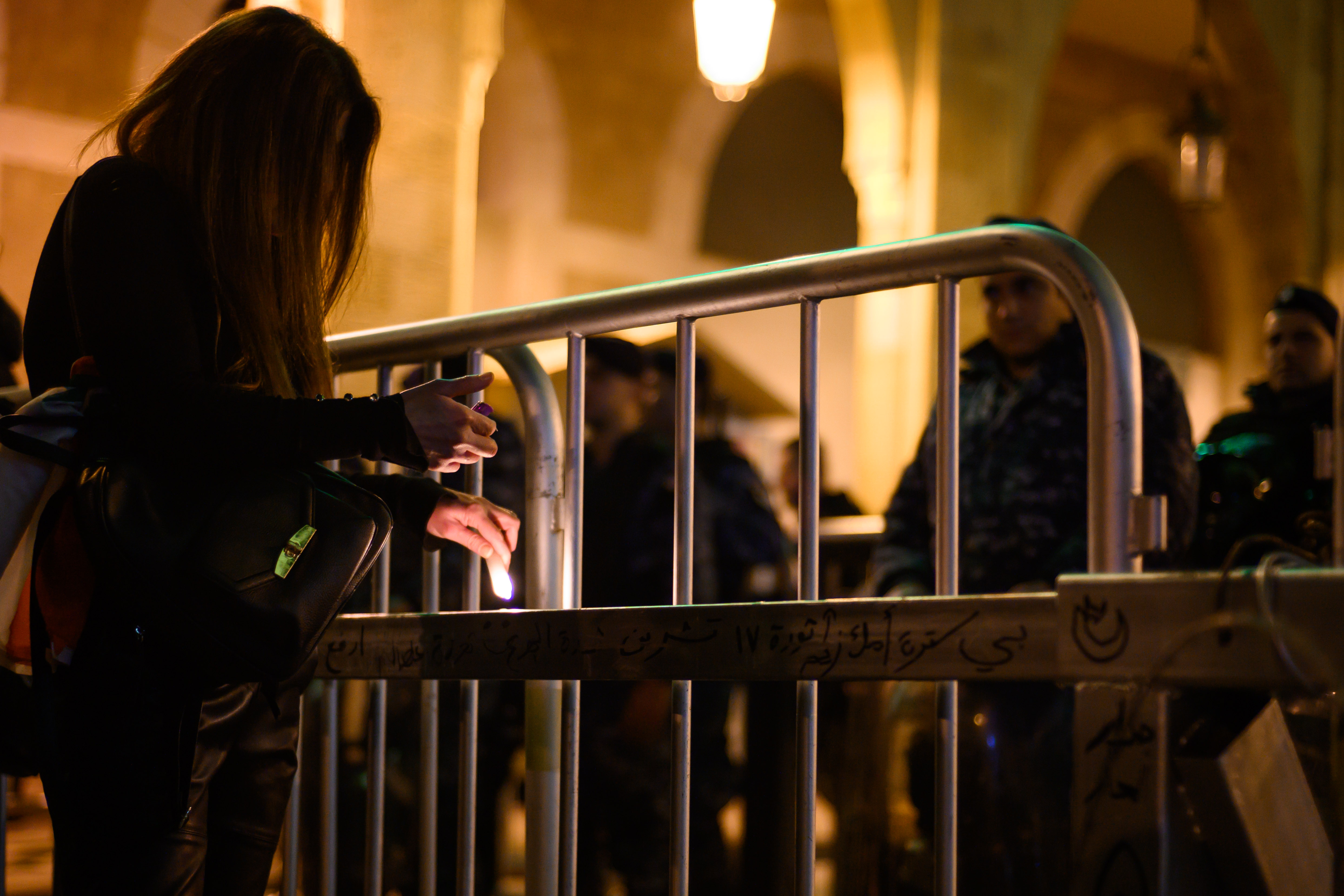 A protestor lights a candle and places it on a newly-erected barricade