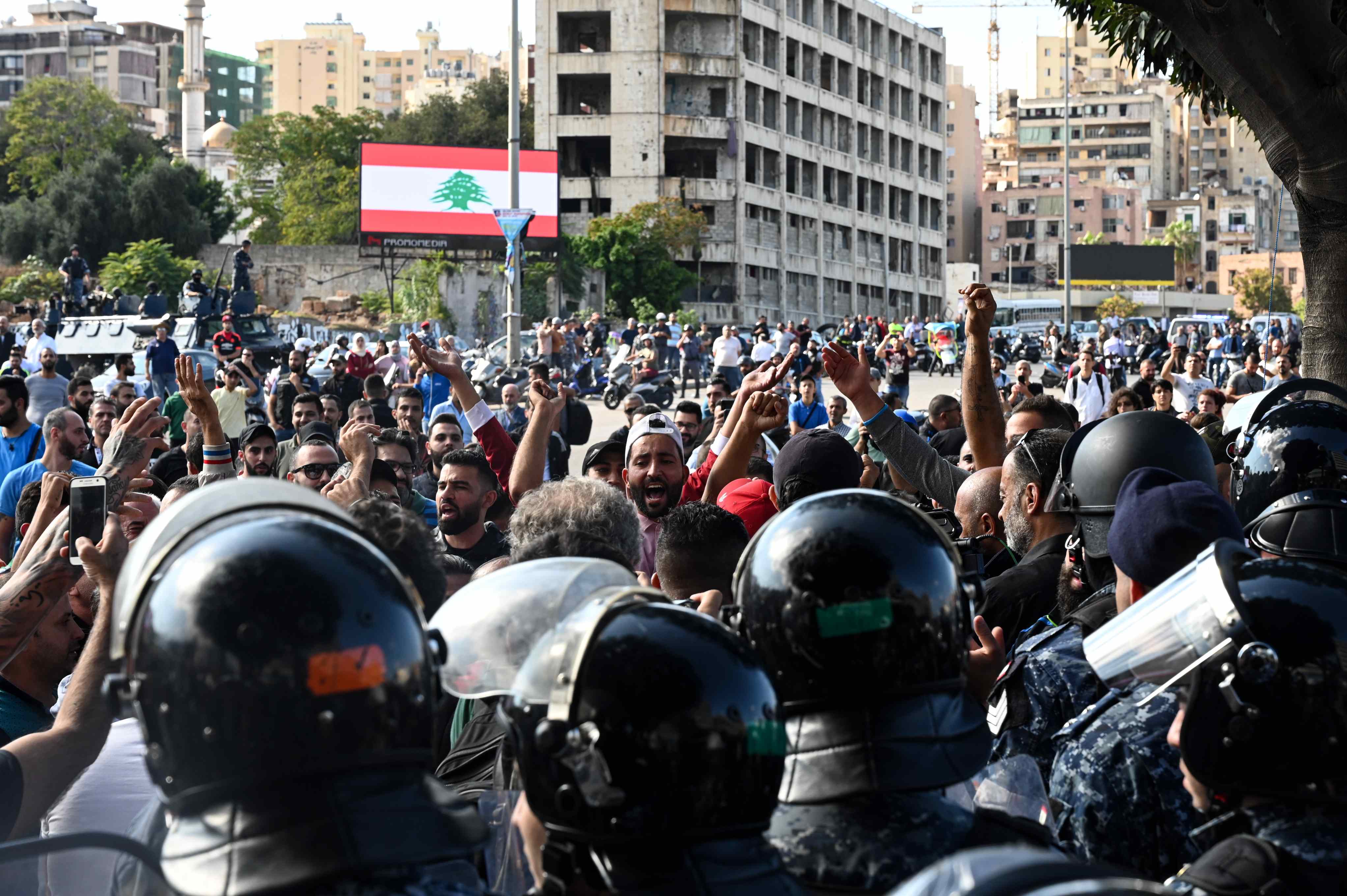 A group of young men, flanked by riot police, chants in support of Speaker of Parliament Nabih Berri (MEE/Finbar Anderson)