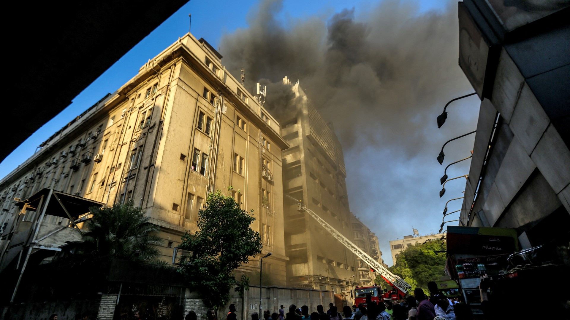 People look on as firefighters douse the flames after a fire broke out in the Telephones landline exchanging station and Ministry of Communications building in the heart of Cairo on 7 July 2025 (AFP)