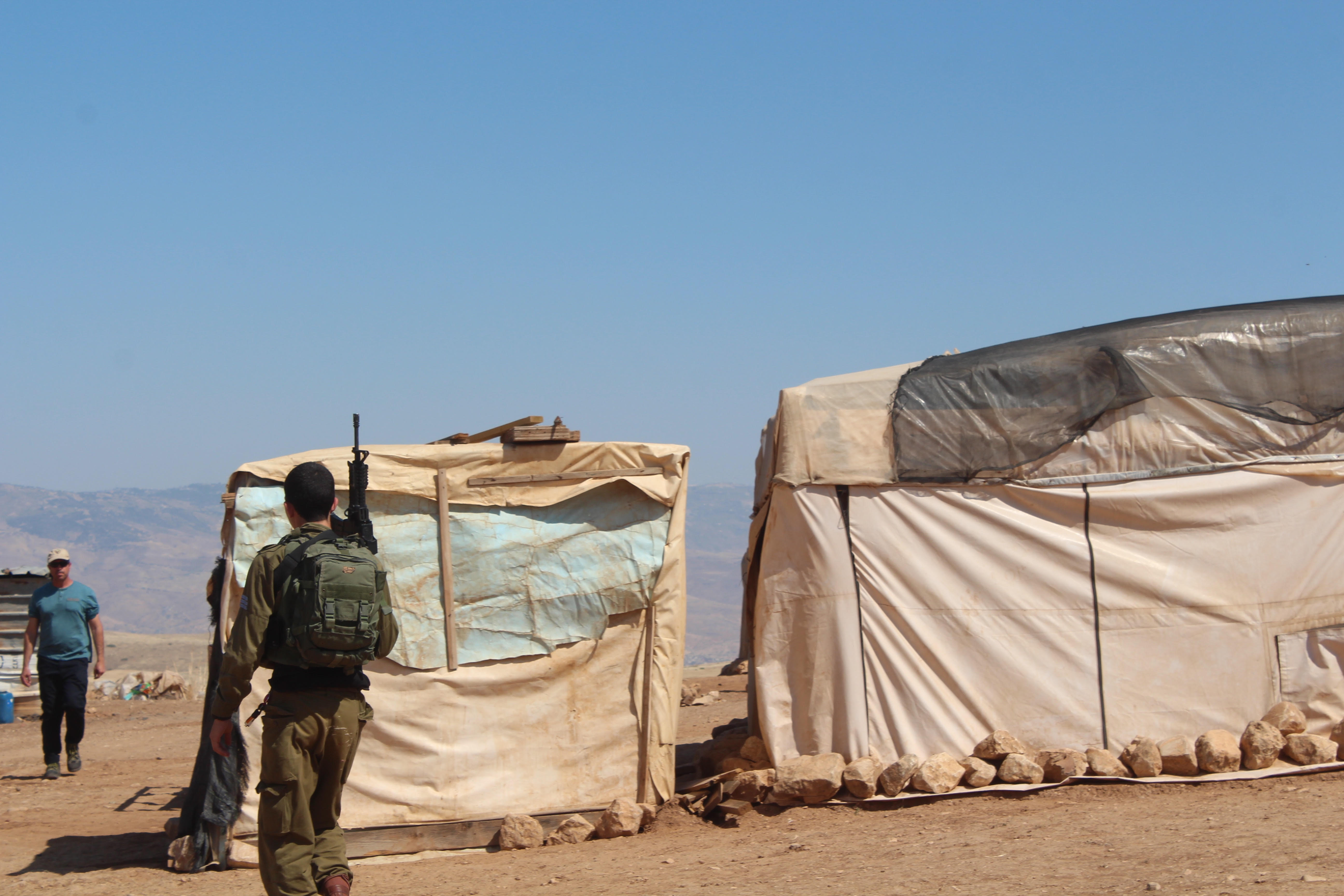 An Israeli soldier patrols the village of Khirbet Humsa al-Fawqa during its eviction (MEE/Shatha Hammad)