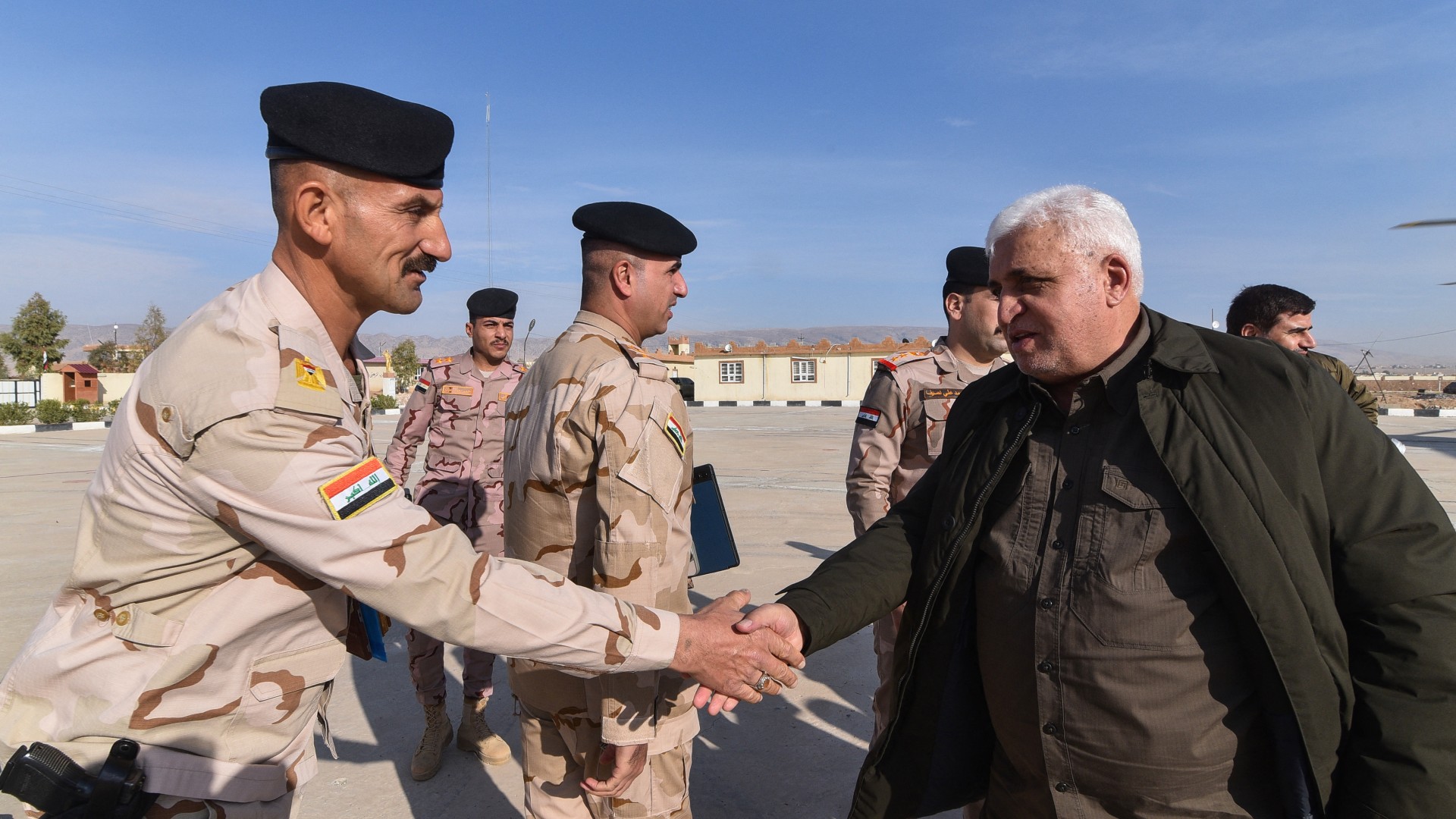 Falah al-Fayadh greeting army officers at the Iraqi-Syrian border on 5 December as Hashd and army forces patrol amid rebel advances in Syria (AFP/Zaid al-Obeidi)