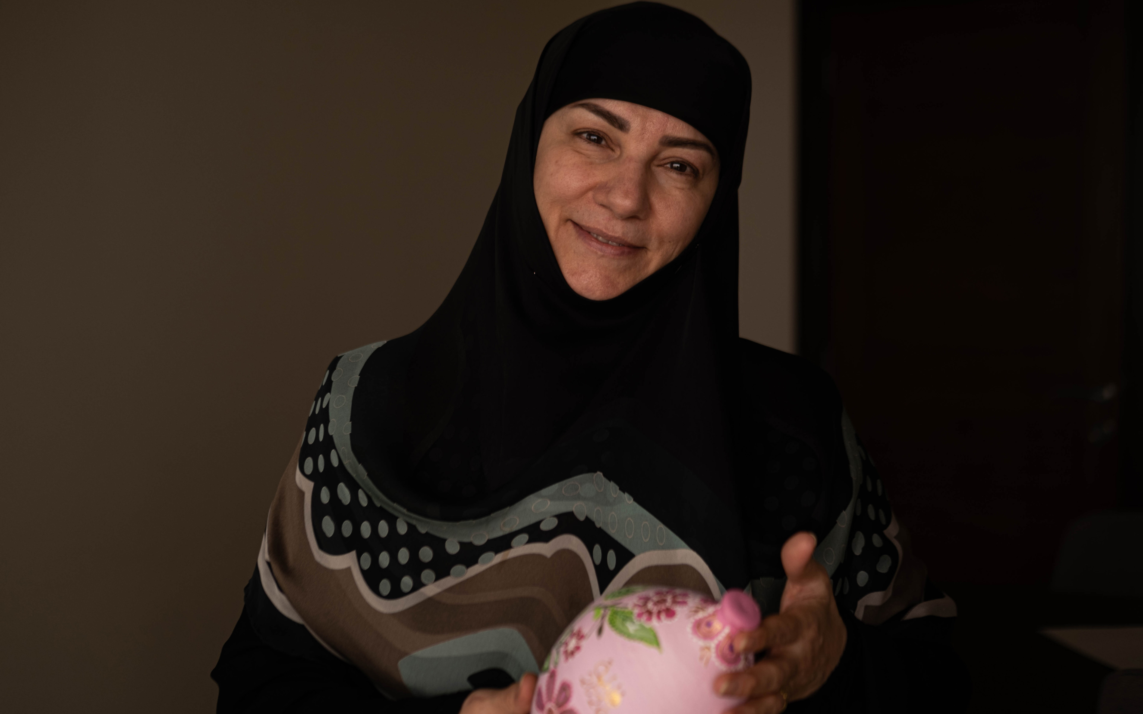 Fatima holds one of her art pieces in her second place of displacement (Zaynab Mayladan/MEE)