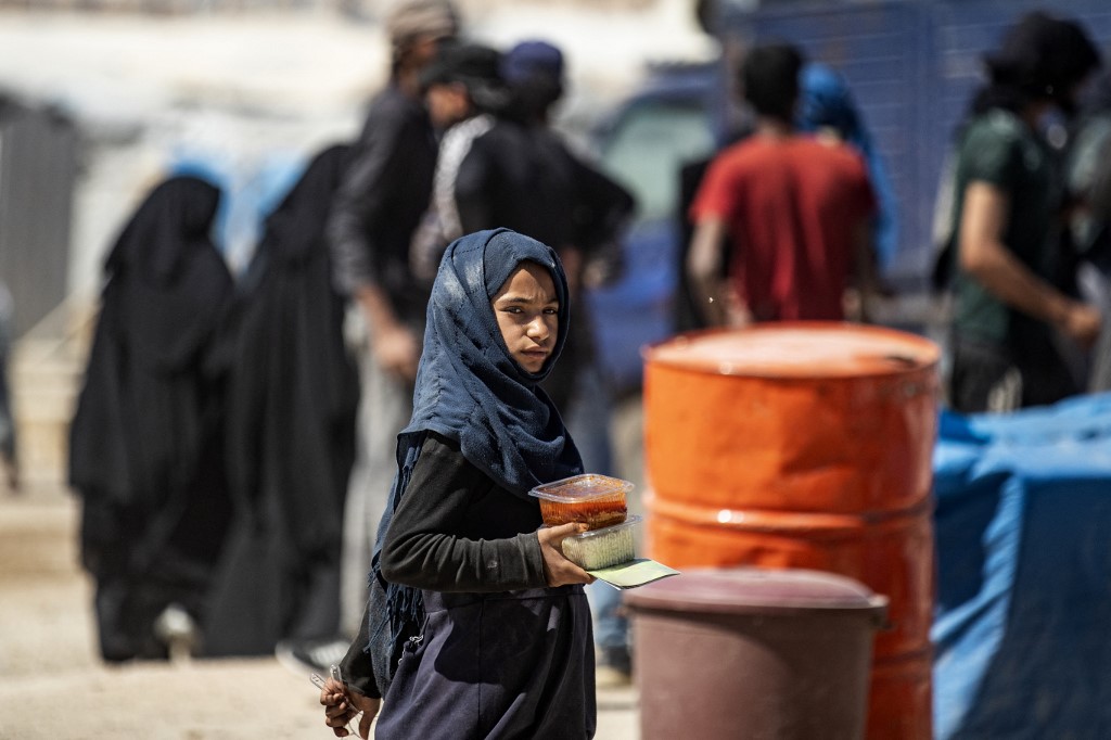 A girl carries a food ration at Syria’s al-Hol camp on 11 May 2021 (AFP)