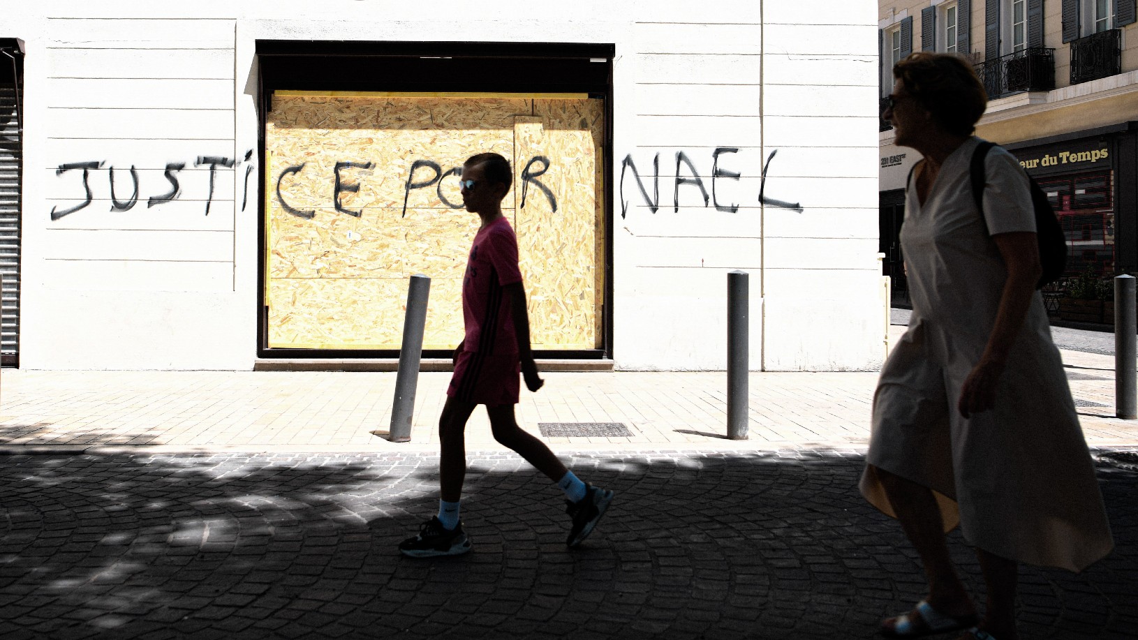 PREVIEW  XML A mother takes a stroll with her son as they pass by a barricaded Nespresso store in Marseille, as a precaution against looting during the riots