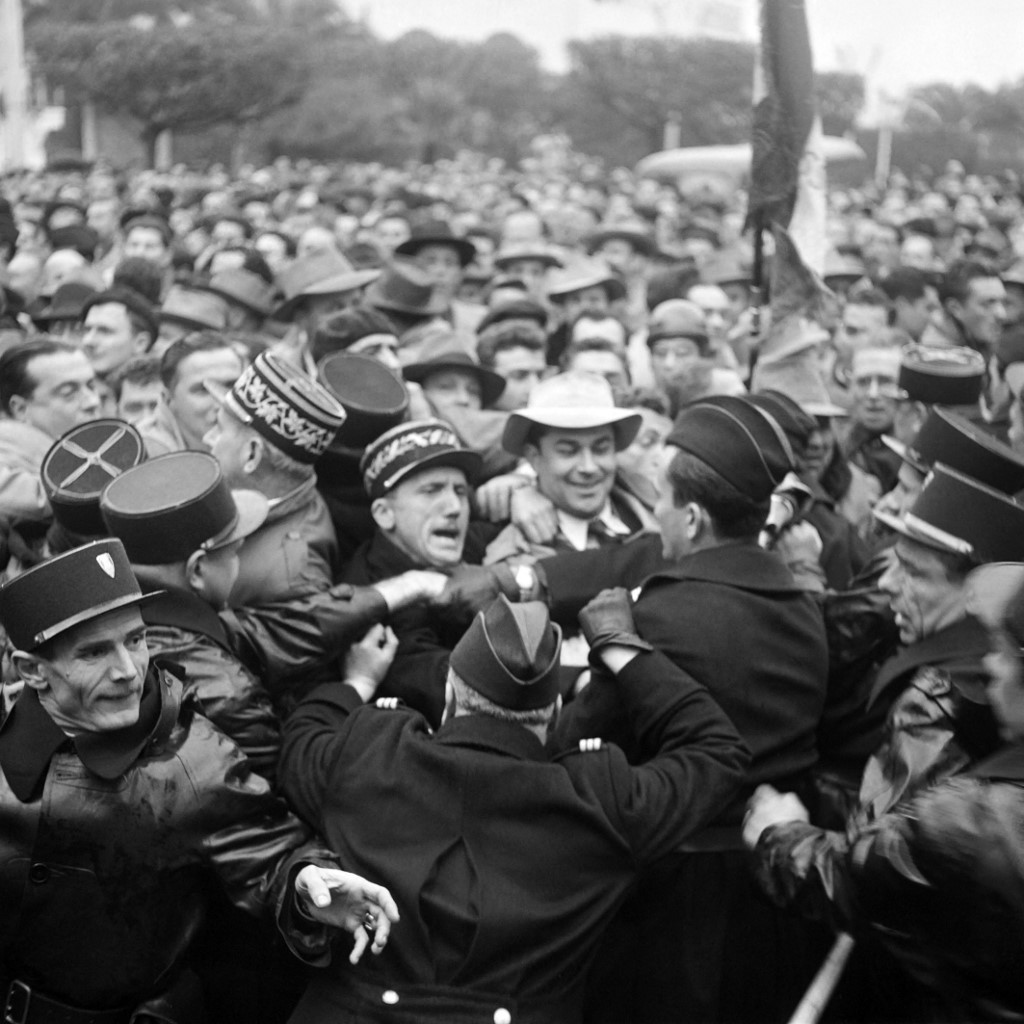 Gendarmes et policiers tentent de contenir les manifestants au centre d’Alger où vétérans et manifestants français se sont rassemblés pour attendre le président du Conseil Guy Mollet, le 6 février 1956 lors de sa visite en Algérie. Des manifestants hostiles au remplacement de Jacques Soustelle par le général Georges Catroux au poste de gouverneur général de l’Algérie accueillent violemment Guy Mollet à Alger. Après cette visite, Guy Mollet décide d'envoyer des contingents d'appelés et de conscrits en Algéri