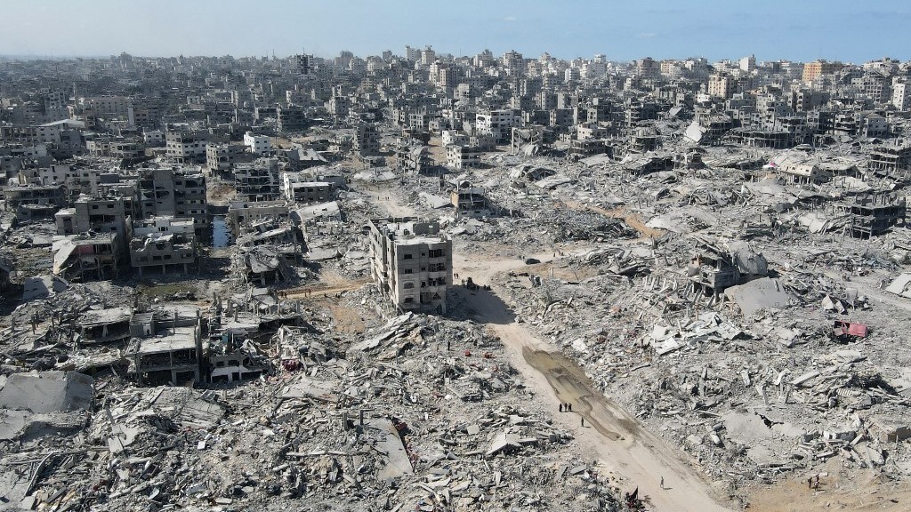In this aerial view, People walk amid the destruction in Gaza City in the northern Gaza Strip on October 11, 2025, a day after a ceasefire took effect (AFP)