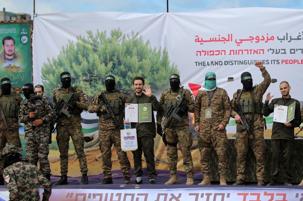 Hamas militants parade newly-released Israeli hostages (L to R) Elia Cohen (behind fighter), Omer Shem Tov and Omer Wankert on stage in Nuseirat in the central Gaza Strip, as part of the seventh hostage-prisoner release on February 22, 2025.