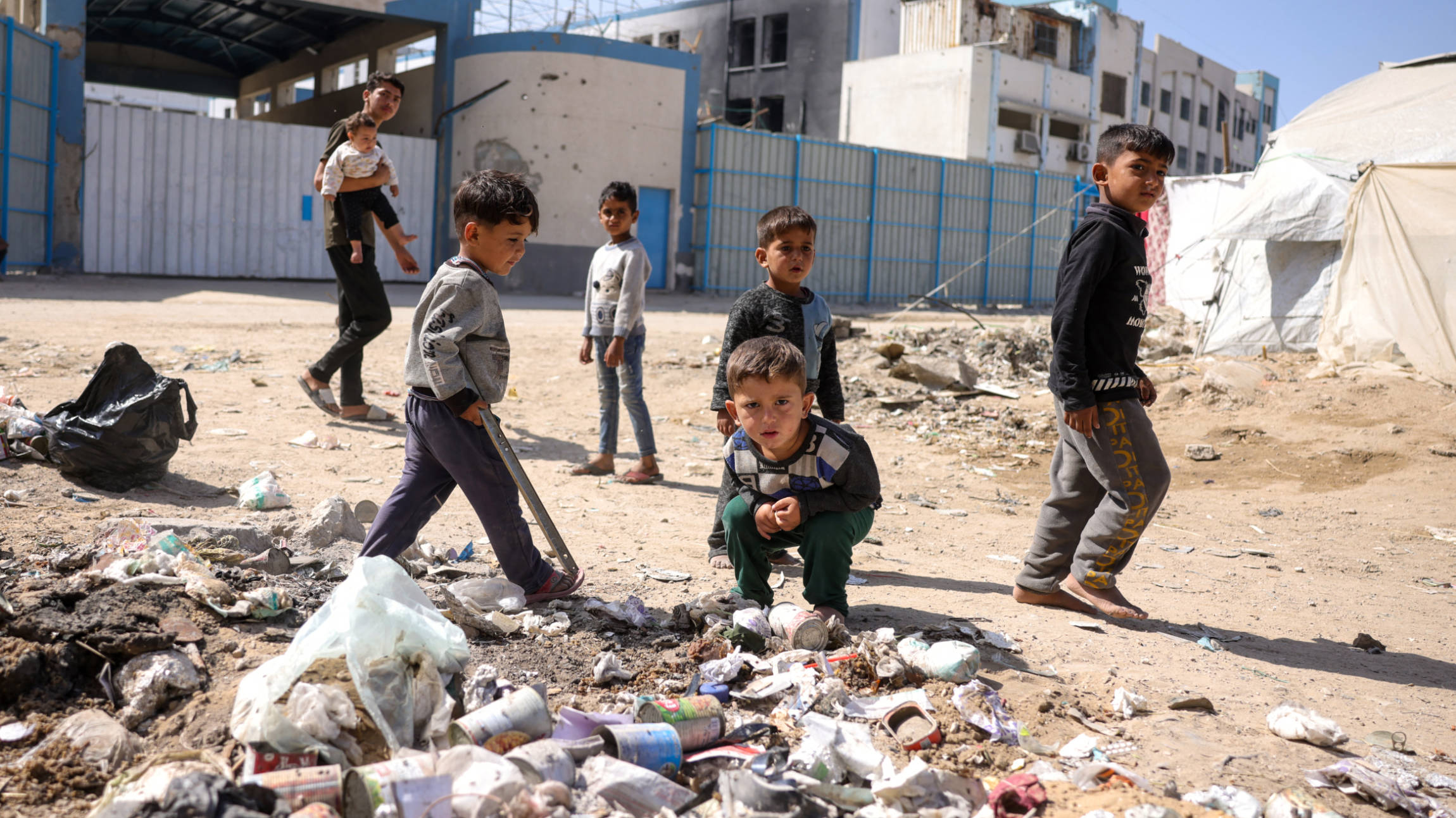 Children play around waste in front of the closed UN agency for Palestinian refugees, Unrwa, headquarters in Gaza City, on 20 May 2025 (AFP)