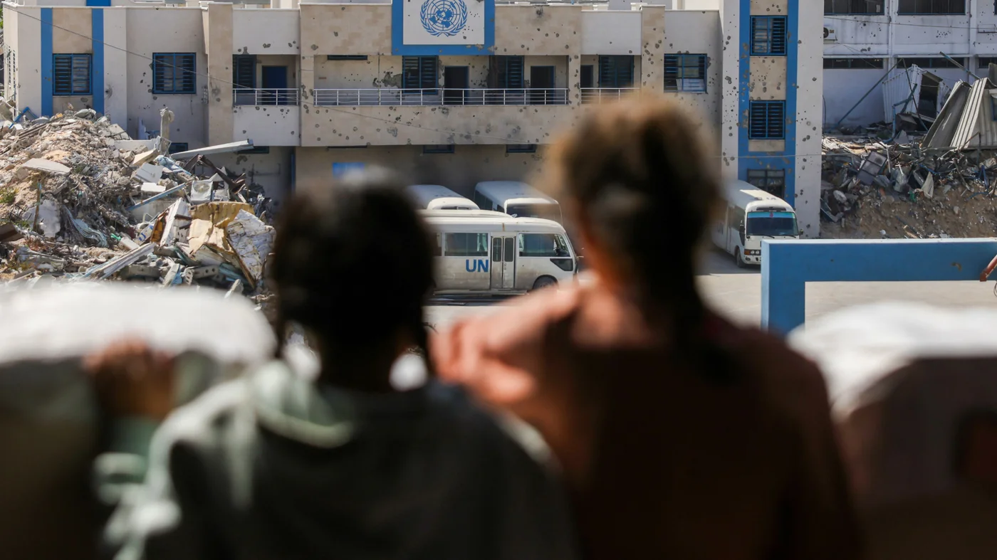 Children stand outside the closed headquarters of the UN agency for Palestinian refugees in Gaza City, on 20 May 2025 (Bashar Taleb/AFP)