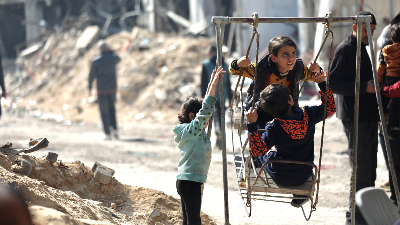 Children play on a swing in amidst the destruction in Gaza City (Mohammed al-Hajjar/MEE).