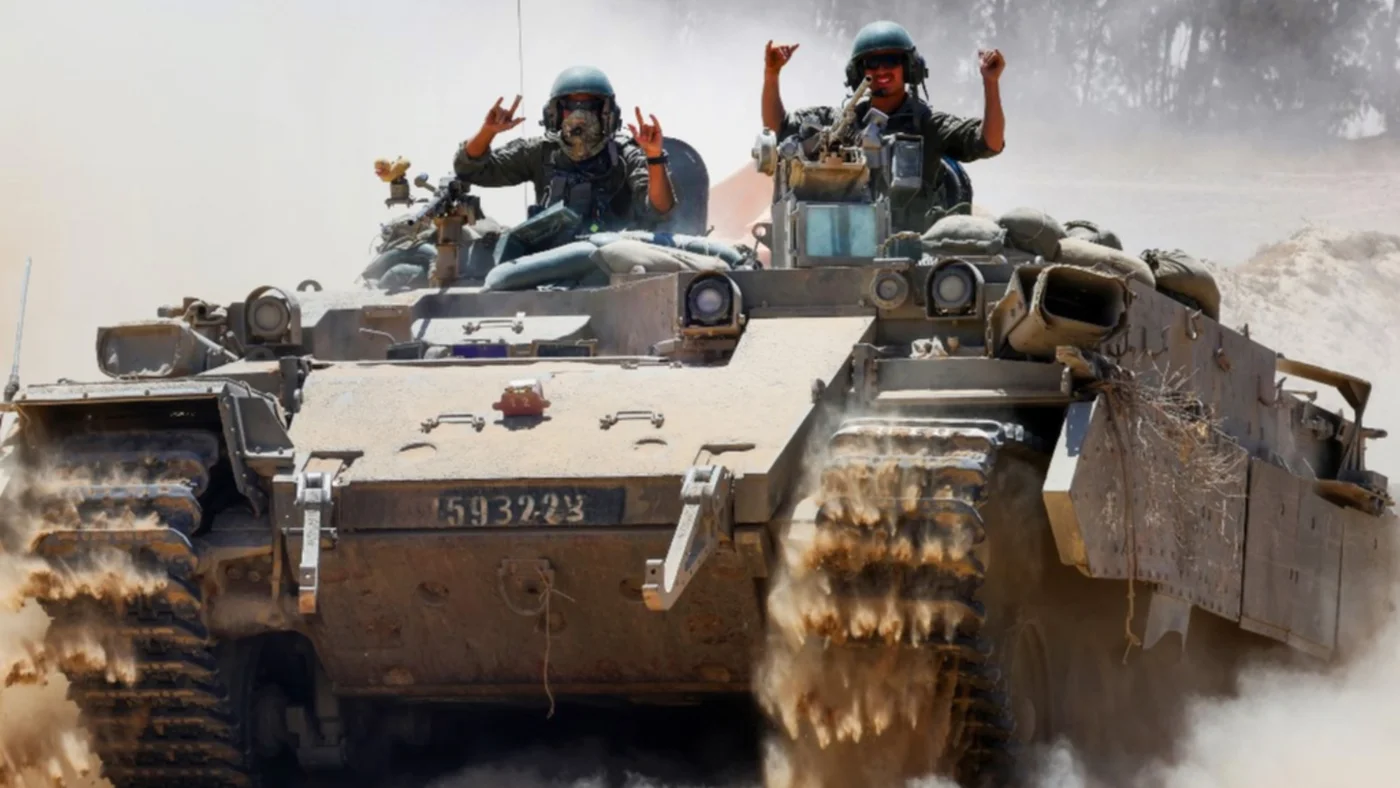 Israeli soldiers gesture atop a military vehicle at Israel's southern border with Gaza on 20 May 2025 (Jack Guez/AFP)