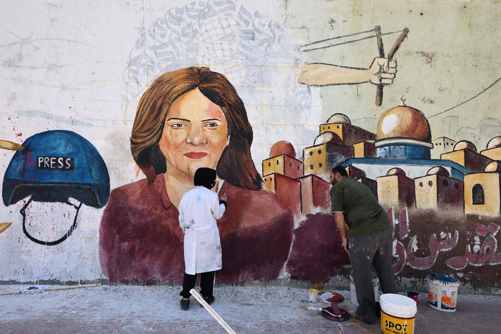 Palestinian artists paint a mural in honour of Abu Akleh in Gaza City on 12 May 2022 (AFP)