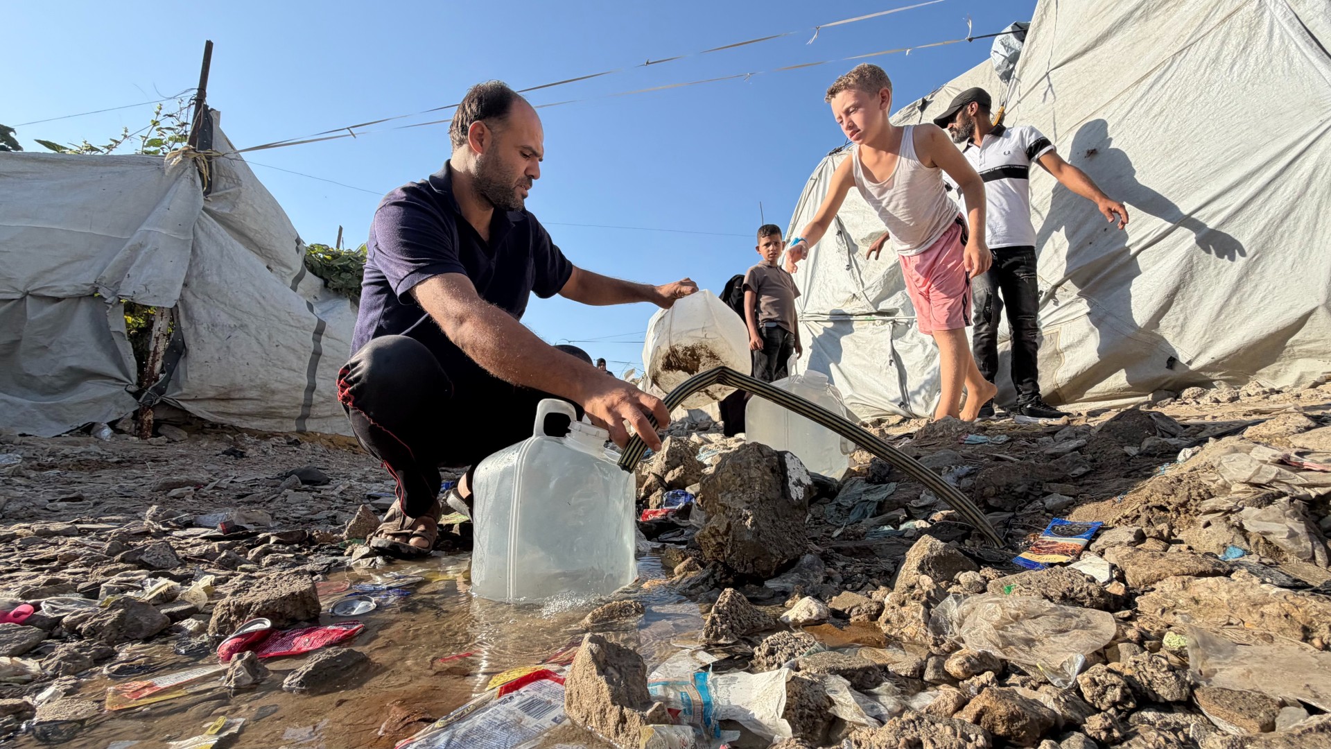 Nihad al-Skafi fills up a water container for his family (Hani Abu Rezeq/MEE)
