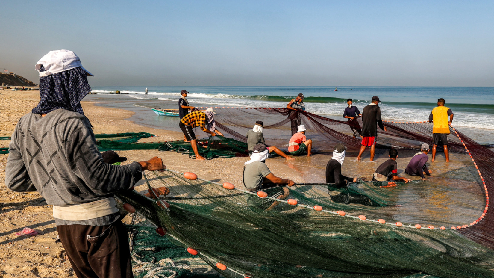 Fishermen pull their nets to retrieve their catch on a beach in the Nuseirat camp for Palestinian refugees in the central Gaza Strip on 30 August 2025 (AFP)