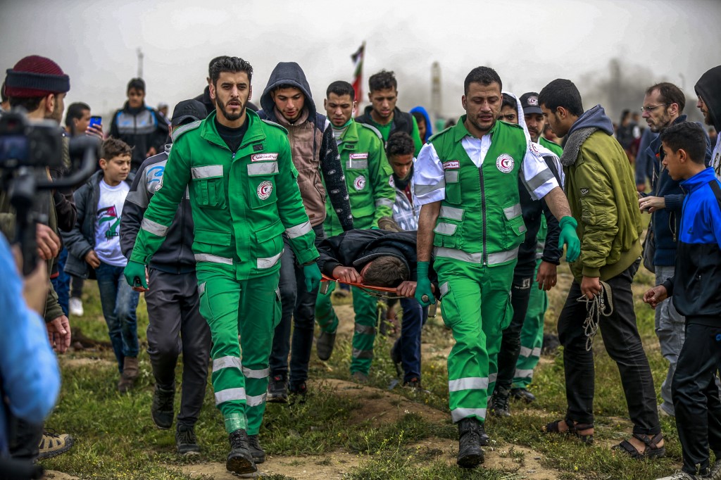 Palestinian paramedics carry away a man on a stretcher after being hit during clashes with Israeli forces following a demonstration marking the first anniversary of the 