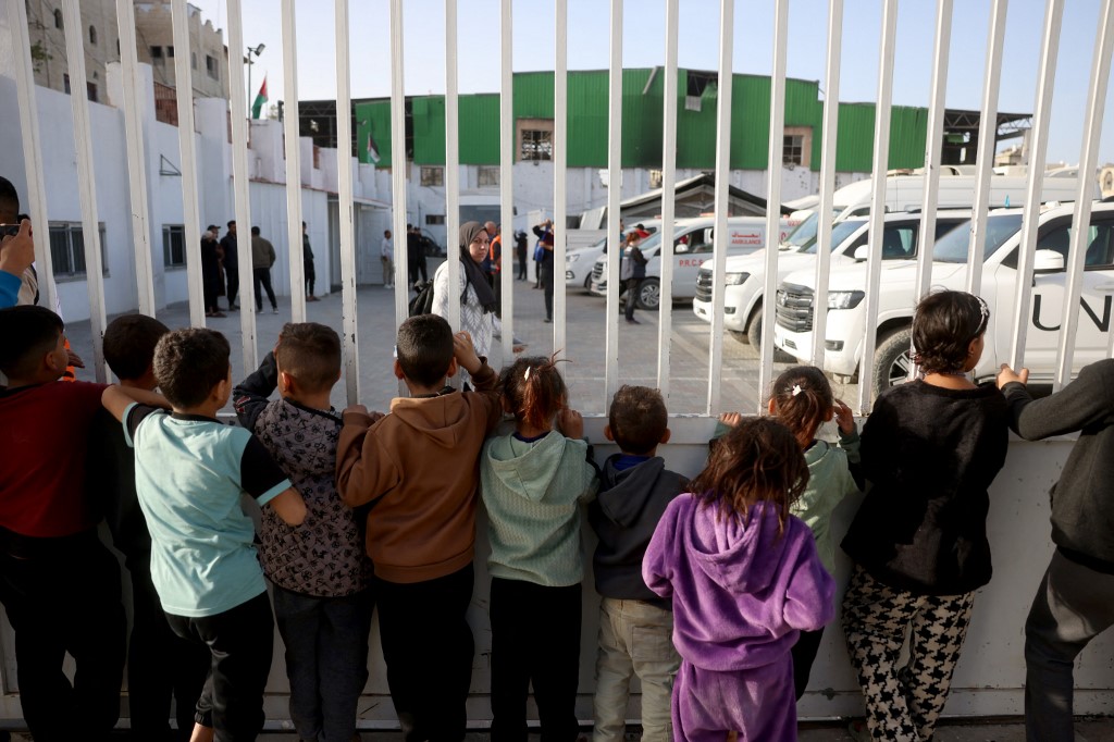 Palestinian children watch as war-wounded Palestinians and other patients prepare to leave the Gaza Strip for treatment through the Rafah border crossing between the Gaza Strip and Egypt after it was opened by Israel for a limited number of people, in Khan Yunis in the southern Gaza Strip, on February 8, 2026