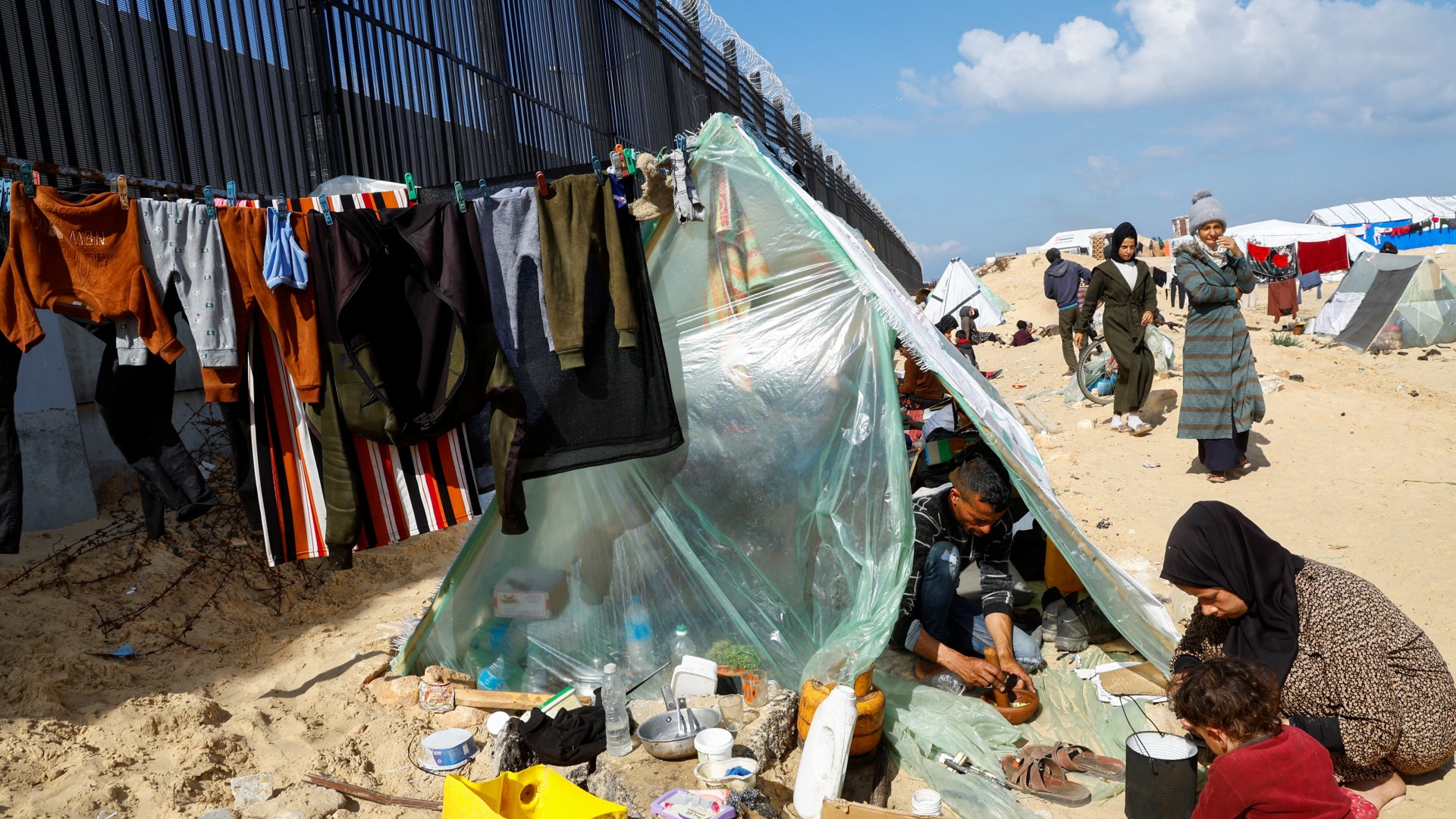 A displaced Palestinian family who fled their house due to Israeli strikes, prepare food as they shelter at the border with Egypt, in Rafah, Gaza, 10 February (Reuters/Mohammed Salem)