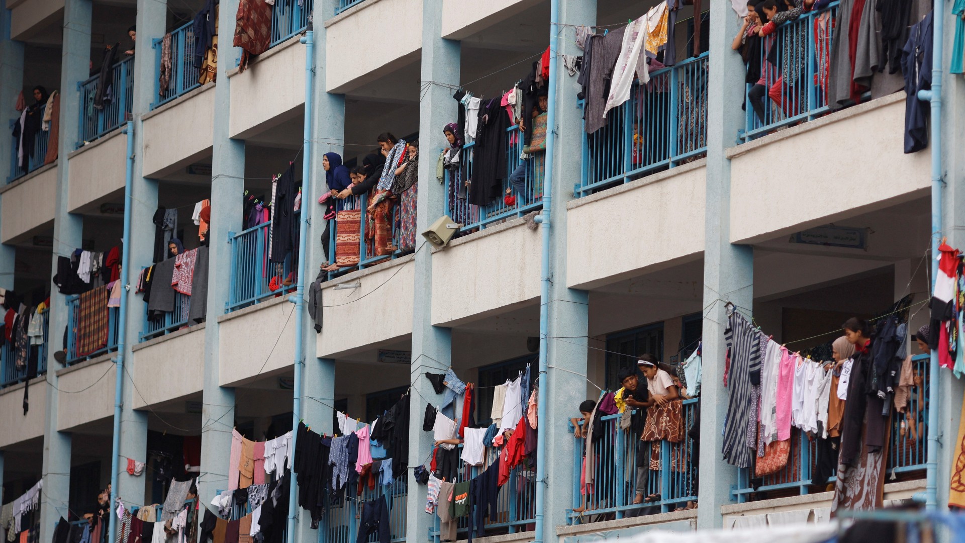 Palestinians, who have fled their homes due to Israeli strikes, watch a nearby Israeli strike as they take shelter in a UN-run school, in Khan Younis in the southern Gaza Strip, October 27, 2023. REUTERS/Mohammed Salem