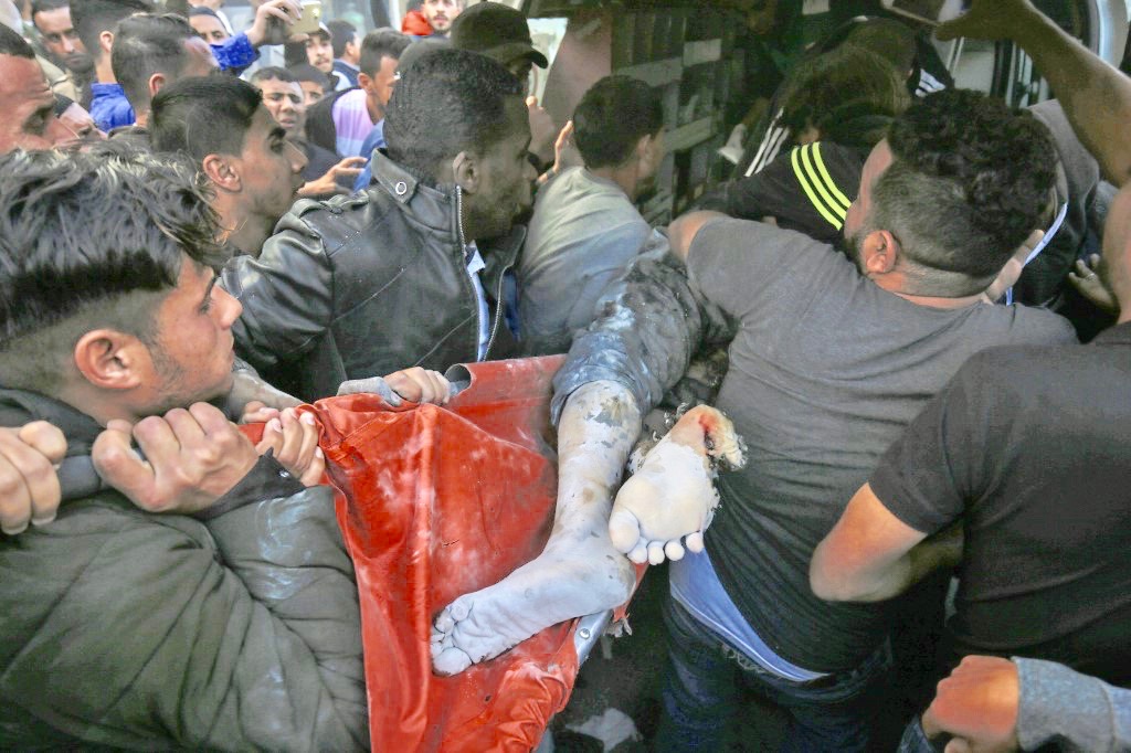 Palestinians carry the body of a man killed by Israeli air strikes from a building in Gaza on Sunday (AFP)