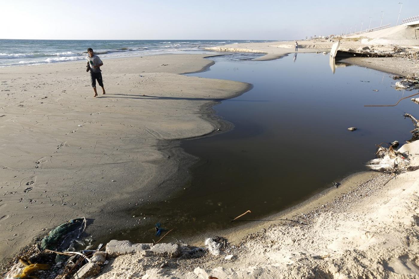 Un Palestinien passe devant des eaux usées déversées dans la mer sur une plage à proximité de Gaza (AFP)