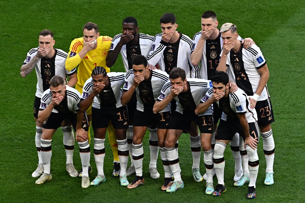 cover their mouths as they pose for the team picture ahead of the Qatar 2022 World Cup Group E football match