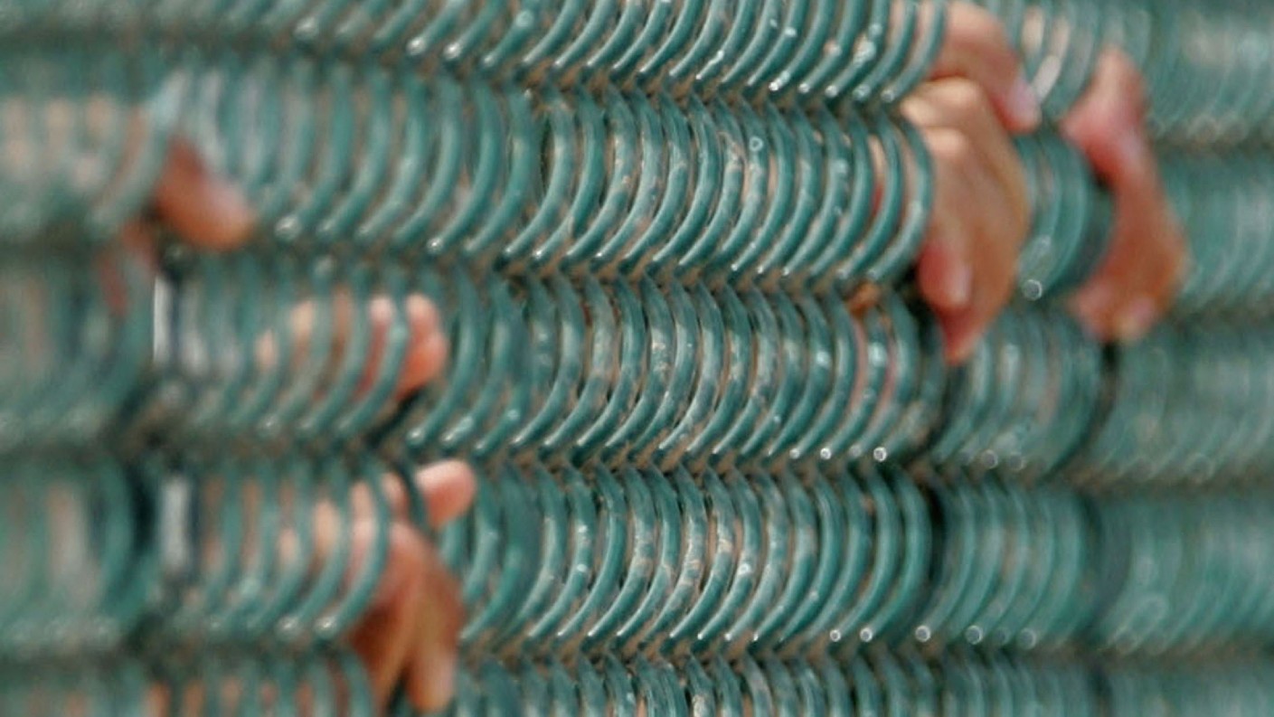 Detainees hold onto a fence at Camp 4 in the Camp Deltamaximum security prison at Guantanamo Bay on 26 August 2004 (Mark Wilson/AFP