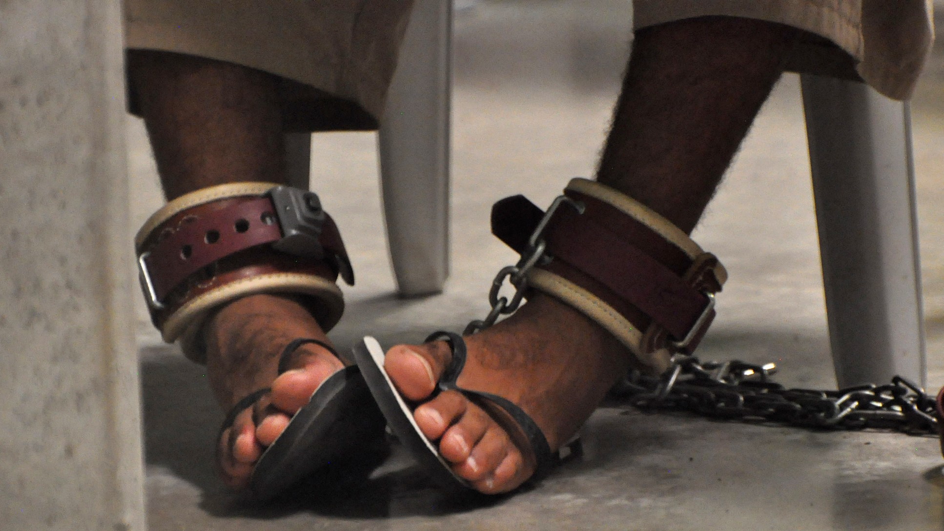 A Guantanamo detainee's feet are shackled to the floor as he attends a 