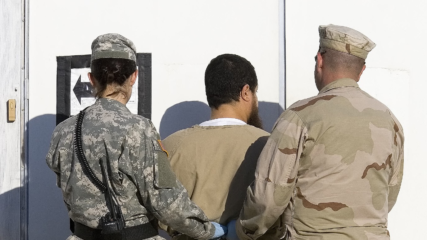 A detainee is escorted by military guards back to his cell after his annual Admistrative Review Board hearing inside Camp Delta's Maximun Security area on 6 December 2006 (Paul J. Richards/AFP)