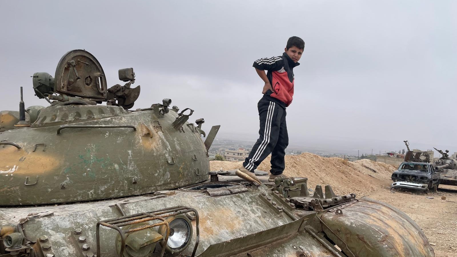 A child plays on a tank on the outskirts of Hama (MEE/Daniel Hilton)