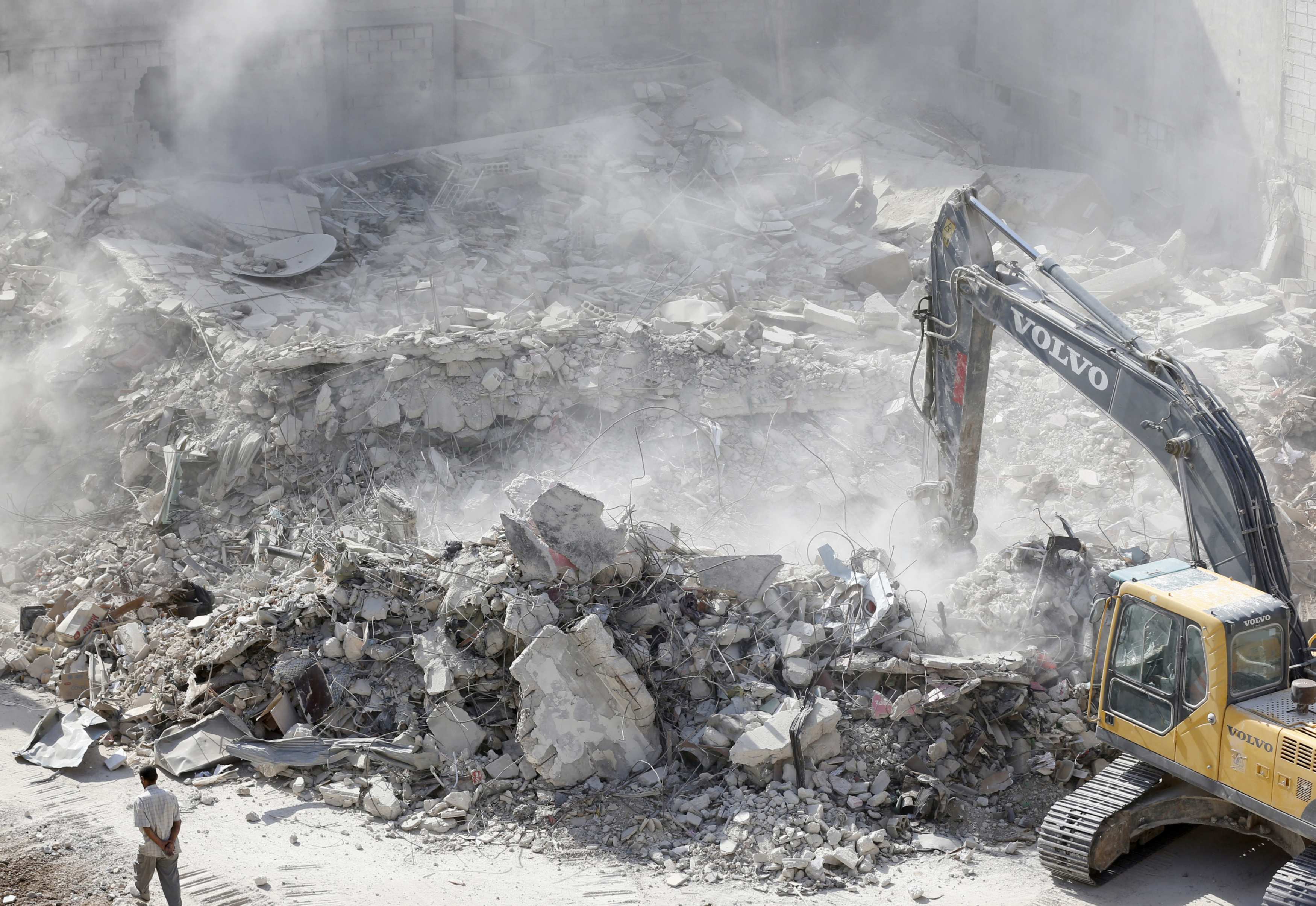 Un bulldozer déblaie les décombres de bâtiments détruits à Harasta, en périphérie de la capitale syrienne Damas, en juillet&nbsp;2018 (AFP)