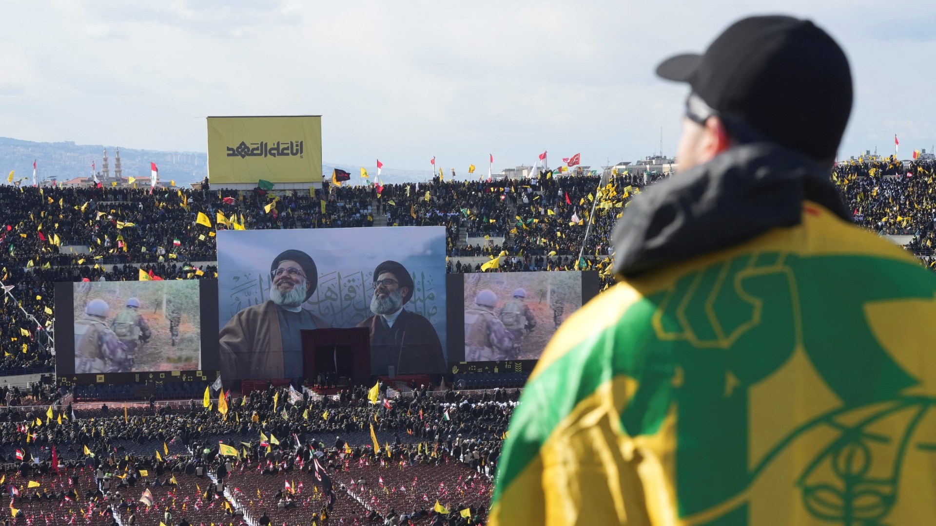 A person with the Hezbollah flag draped over his shoulders looks on during the day of a public funeral of Hassan Nasrallah and Hashem Safieddine (Reuters/Mohammed Yassin)