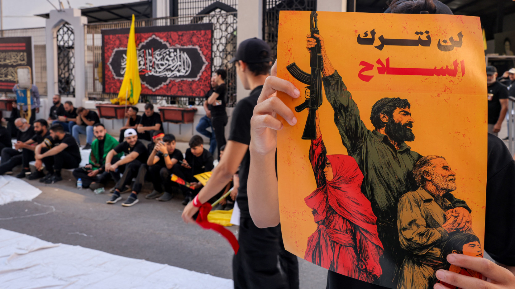 A person holds a sign with the Arabic slogan 