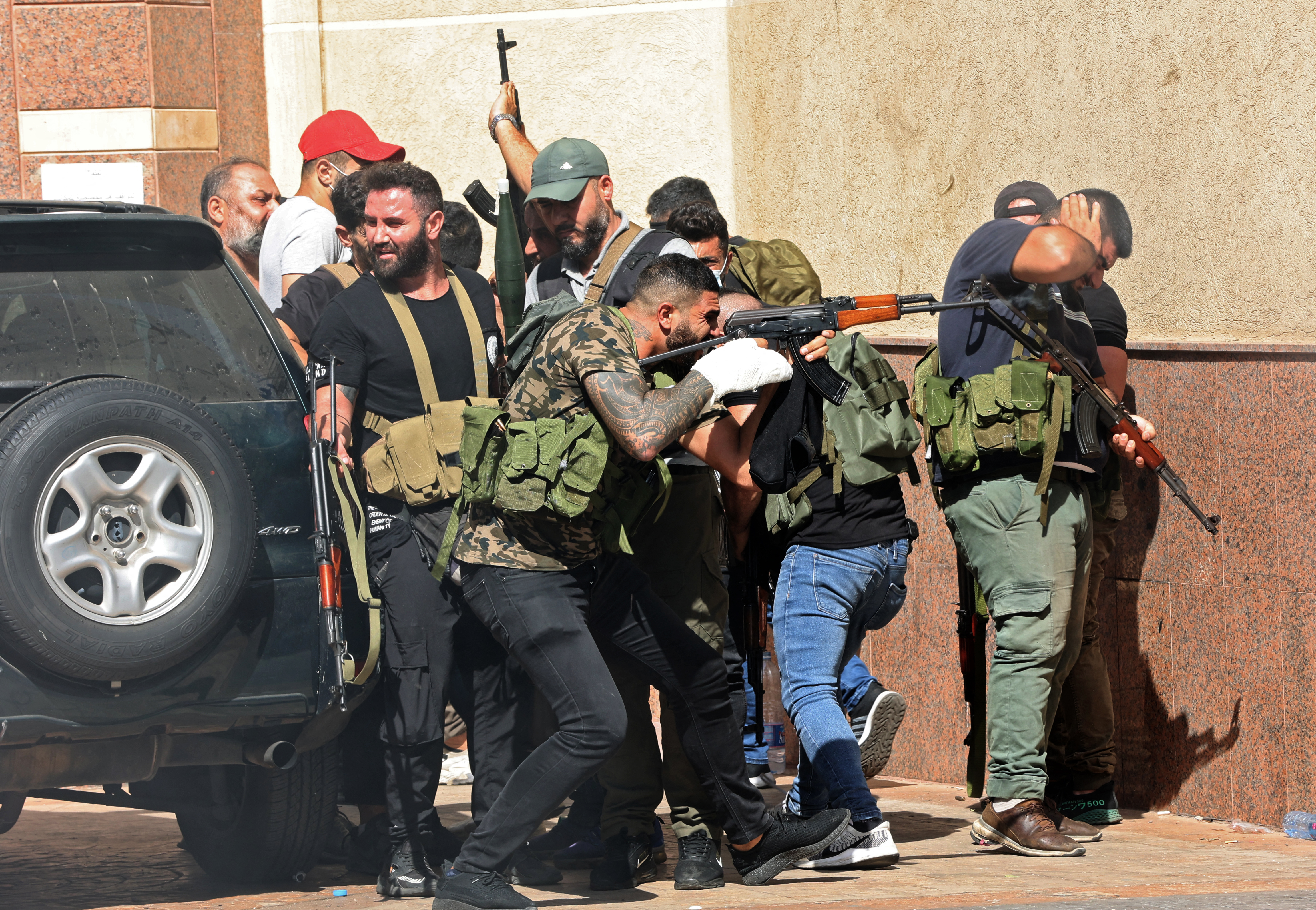 Fighters from Hezbollah and Amal movements take aim during clashes in the area of Tayouneh, in the southern suburb of the capital Beirut, on 14 October 2021 (AFP)