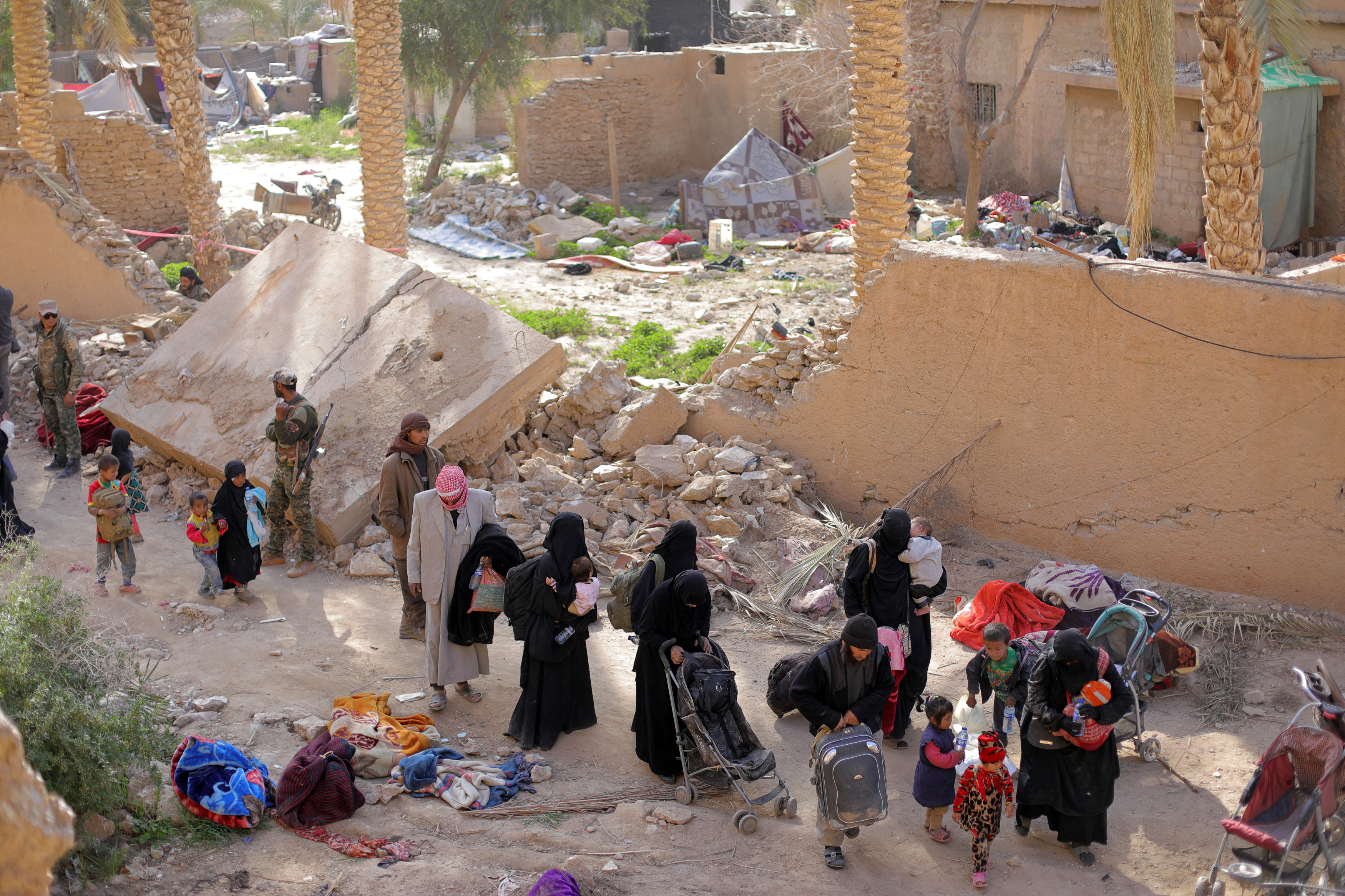 Islamic state fighters and their families walk as they surrendered in the village of Baghouz (Reuters)