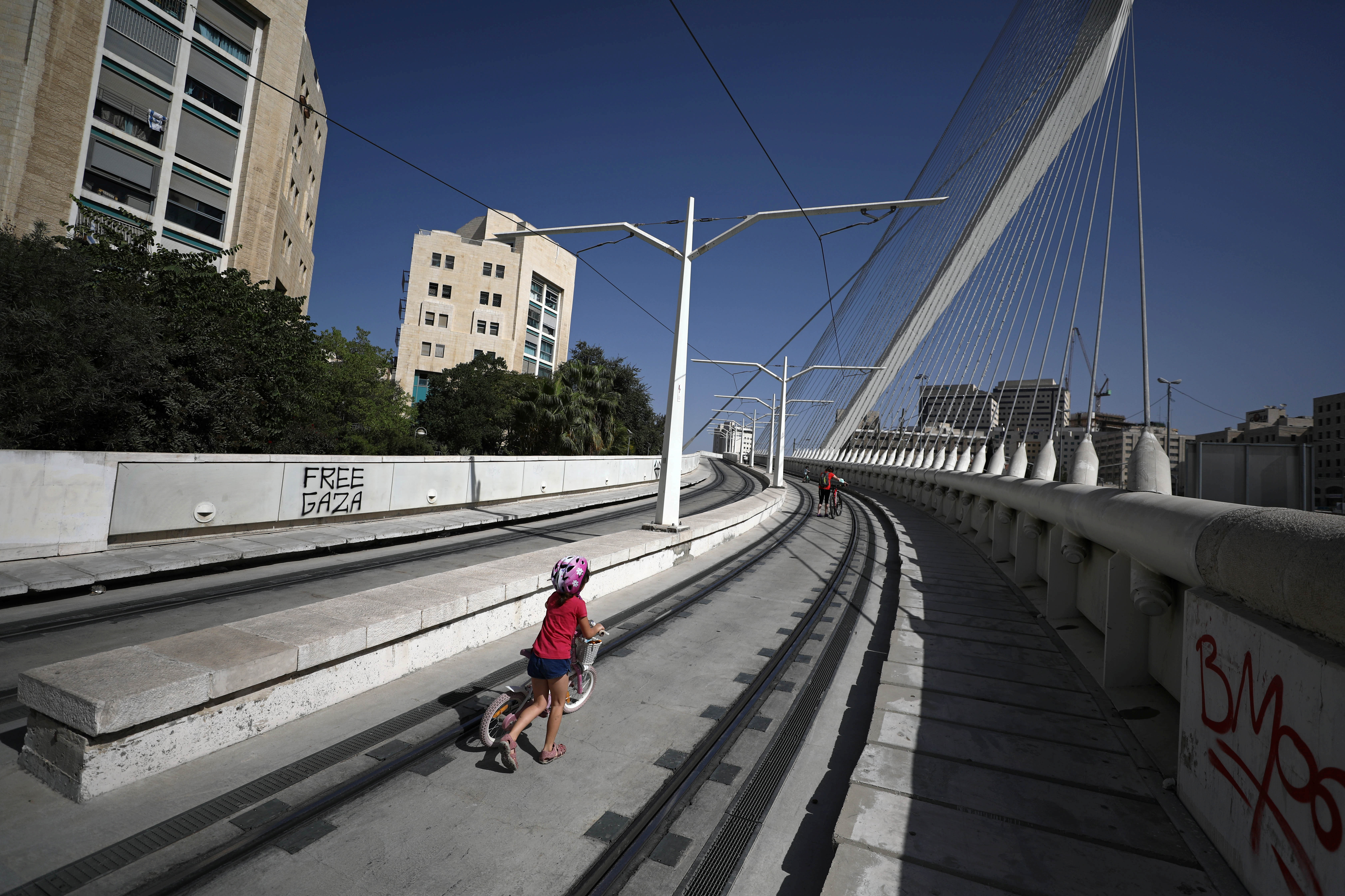 A girl pushes her bicycle along the tracks of the deserted light railway that runs through central Jerusalem