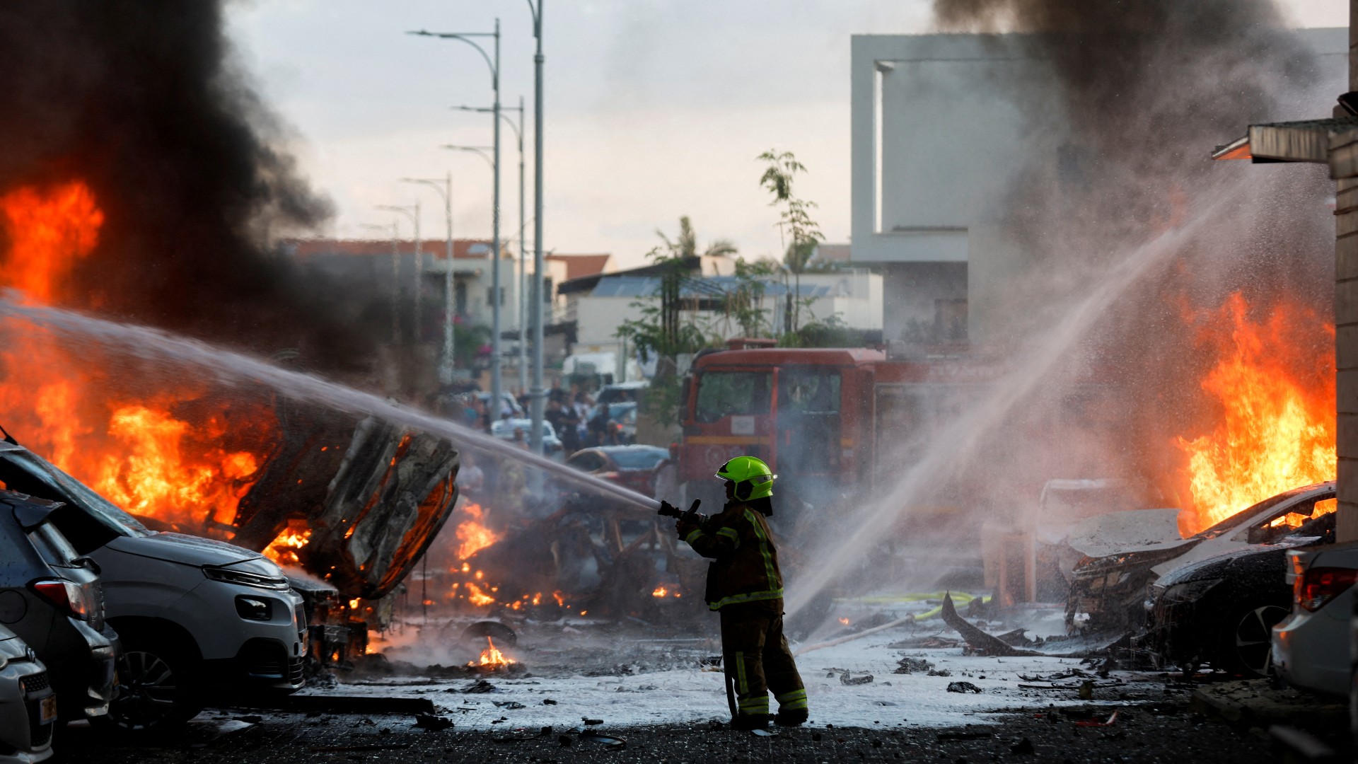 An emergency personnel works to extinguish the fire after rockets are launched from the Gaza Strip, as seen from the city of Ashkelon (Reuters)