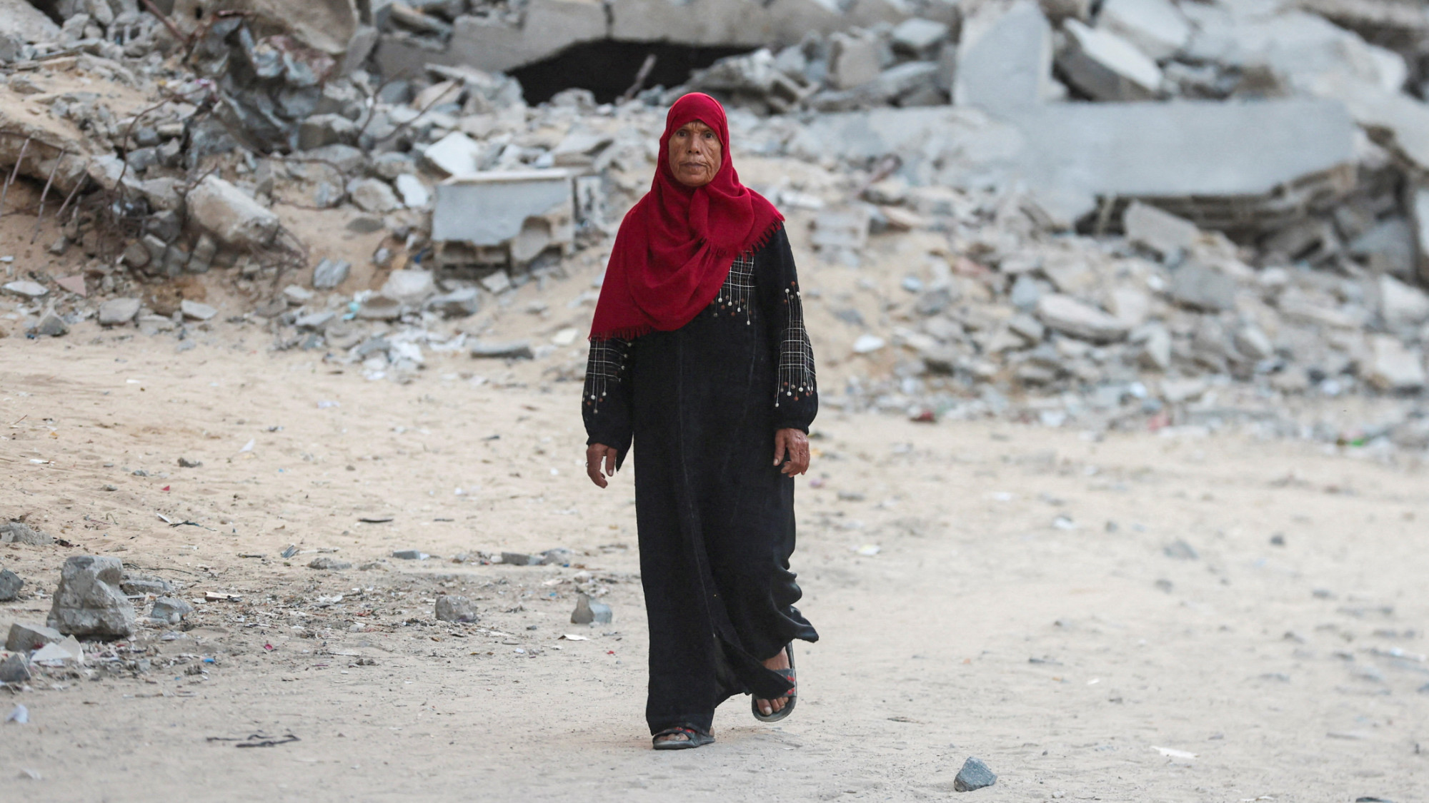 A Palestinian woman walks near rubble after US President Donald Trump announced that Israel and Hamas agreed on the first phase of a Gaza ceasefire, in Khan Younis in the southern Gaza Strip 9 October 2025 (Reuters/Ramadan Abed)